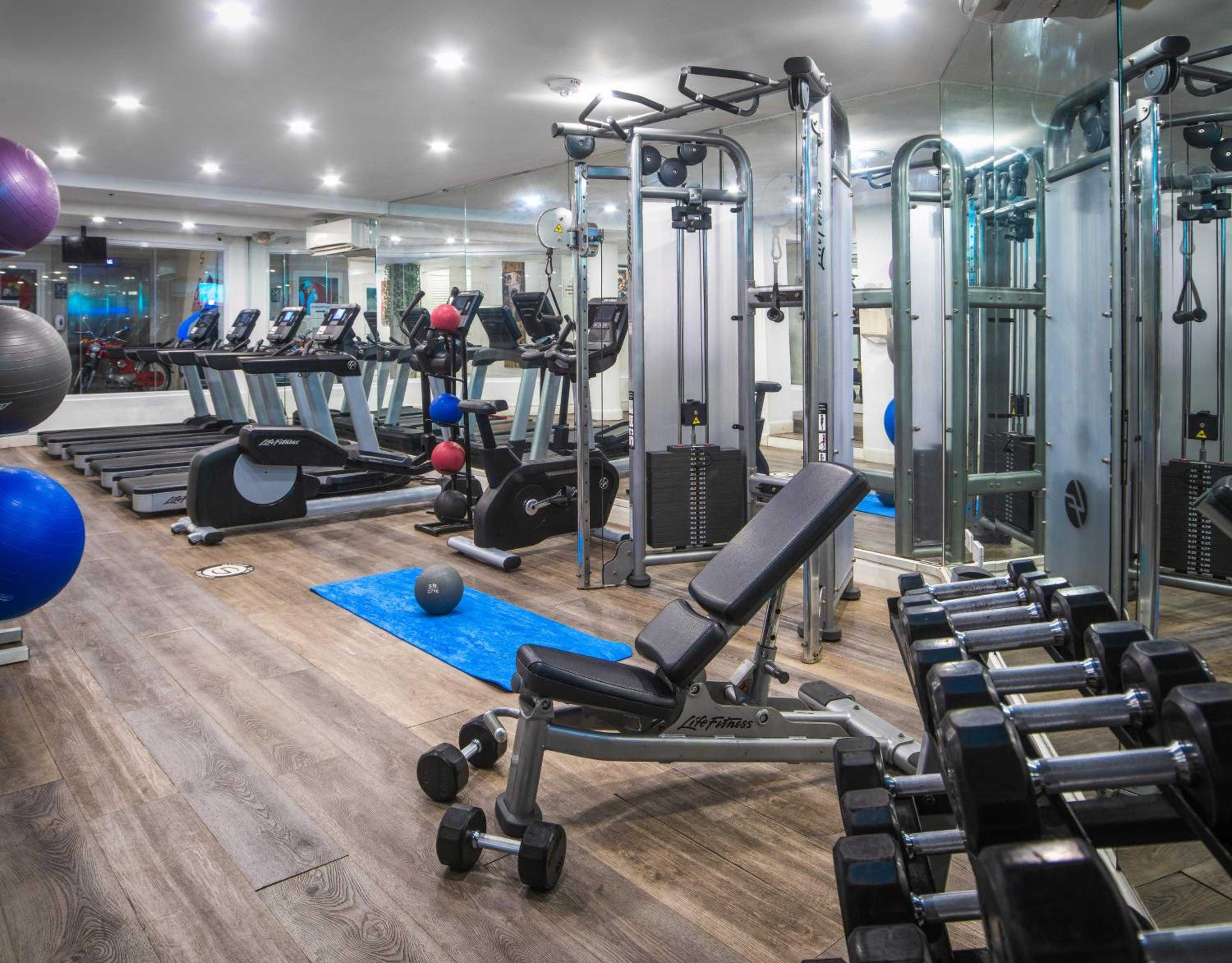State-of-the-art equipment gleams under bright LED lighting in this expansive fitness center, where polished wood floors and mirrored walls create an energizing workout sanctuary.