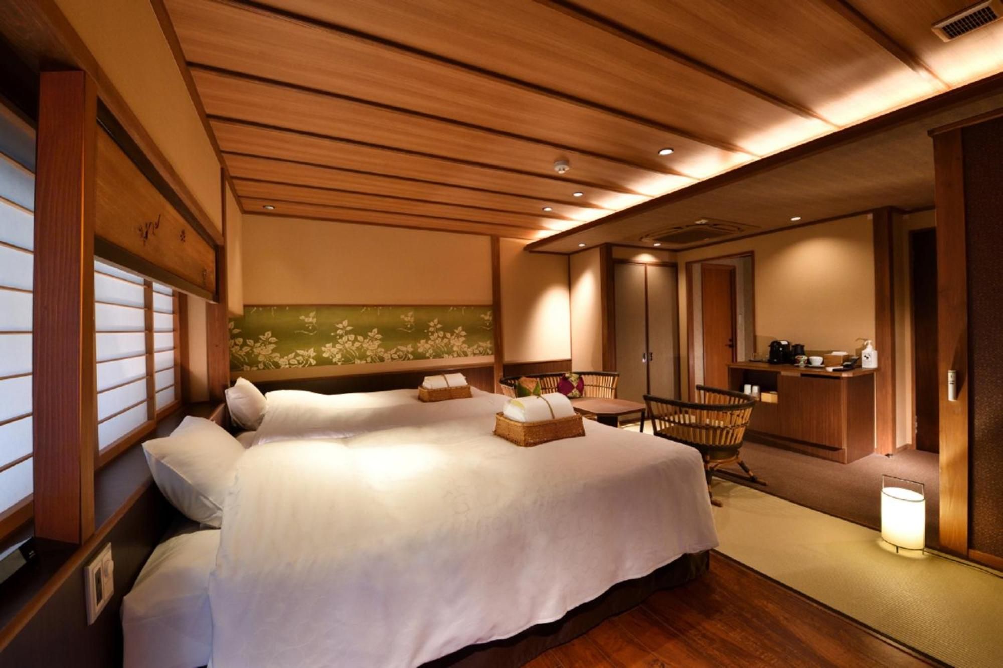 Warm wood beams frame this serene suite where traditional shoji screens filter golden light across crisp white linens and handwoven tatami mats.