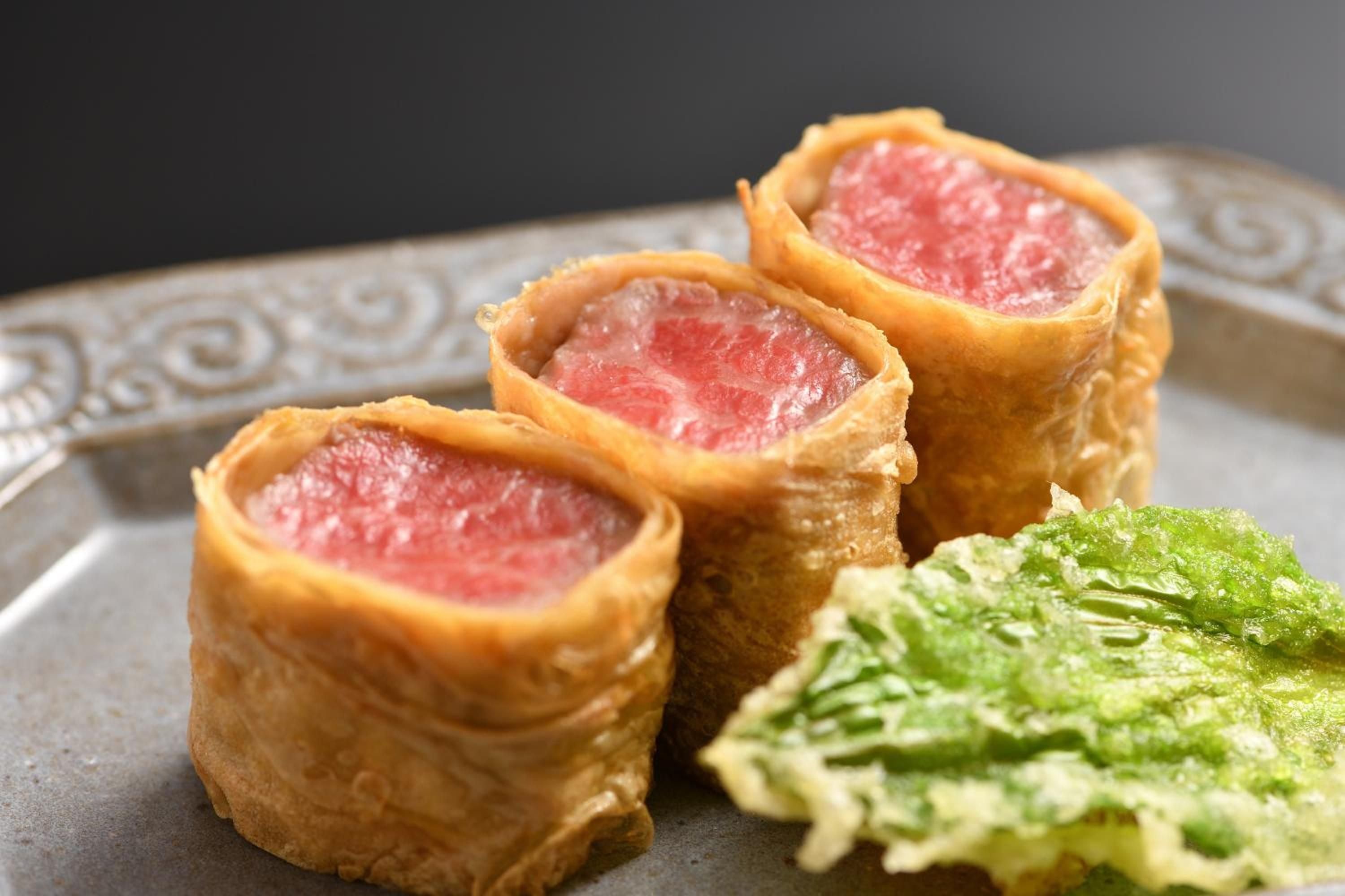 Delicate beef wellington rolls arrive perfectly seared, their flaky pastry shells revealing ruby-red centers alongside vibrant wasabi—culinary artistry that defines refined Japanese hospitality.