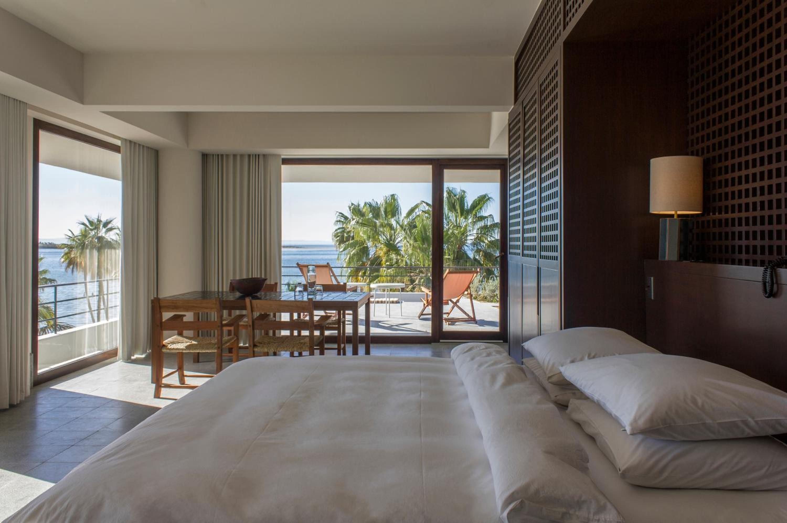 Crisp white linens frame panoramic Sea of Cortez views from this oceanfront suite, where woven leather chairs and warm wood invite lazy afternoons watching palm fronds dance.