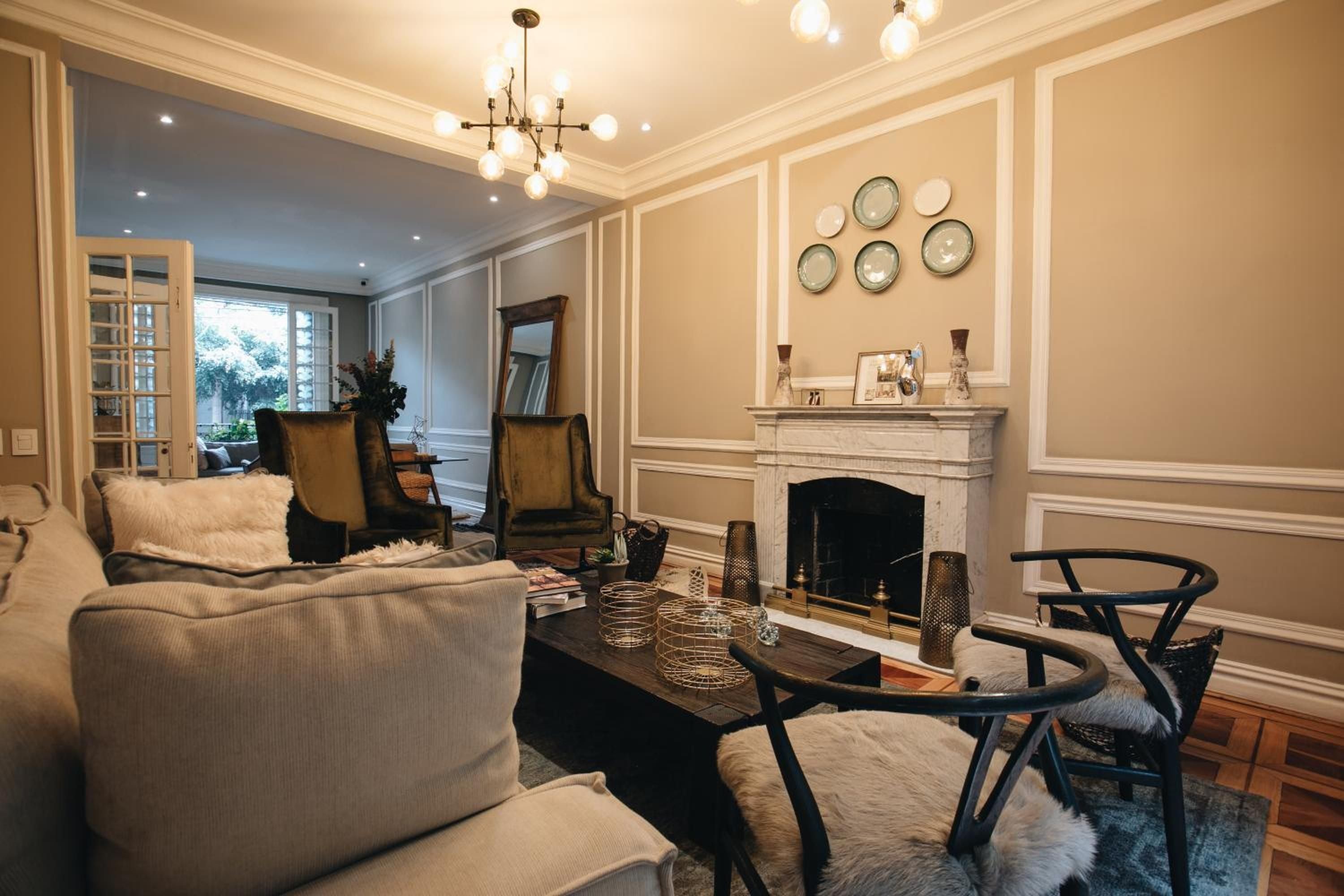 Warm amber lighting and contemporary furnishings create an inviting living space where guests gather around the crackling fireplace beneath displays of artisanal ceramics.
