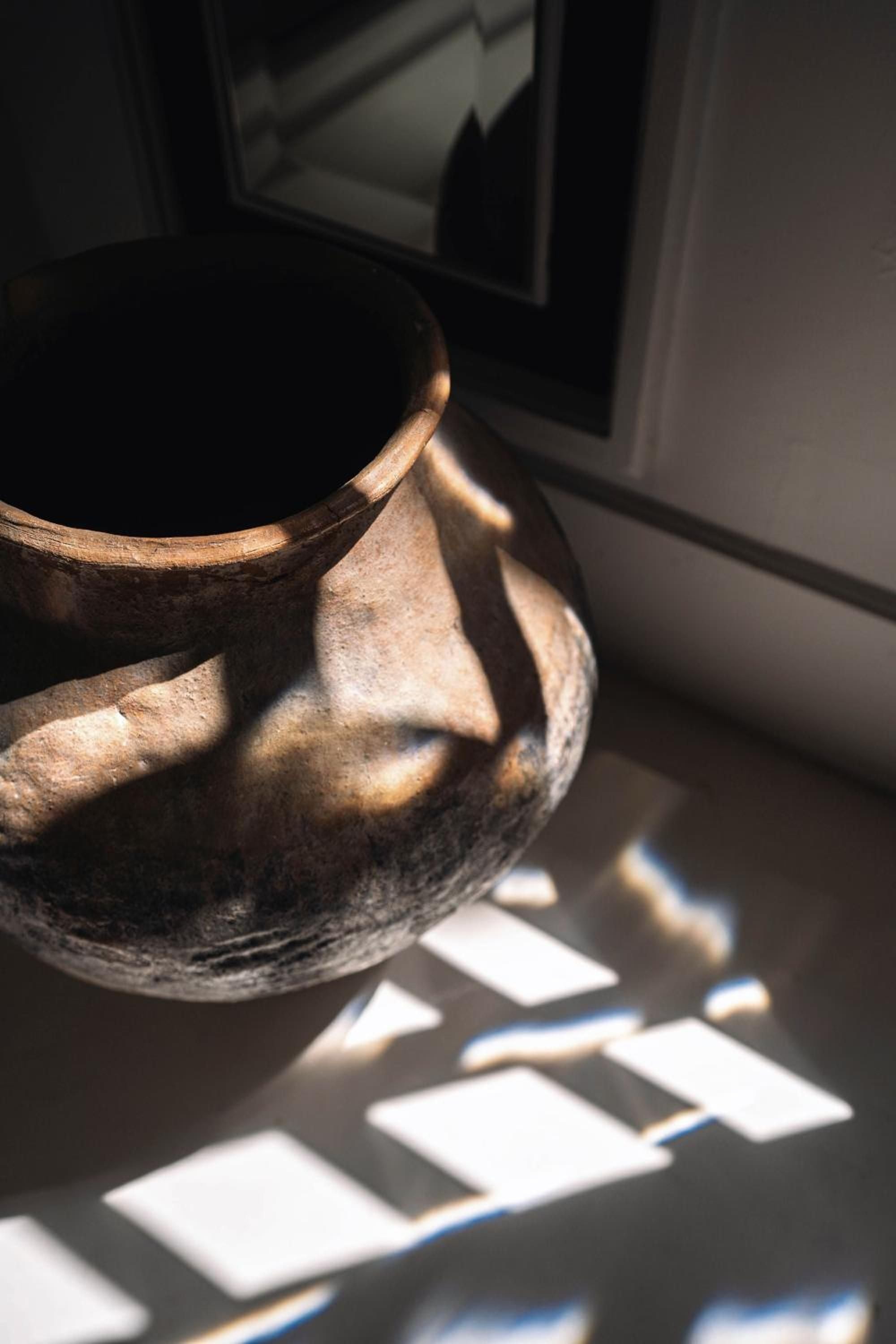 Handcrafted pottery catches golden afternoon light alongside scattered photographs, revealing the hotel's thoughtful curation of local artisanal touches and personal storytelling elements.