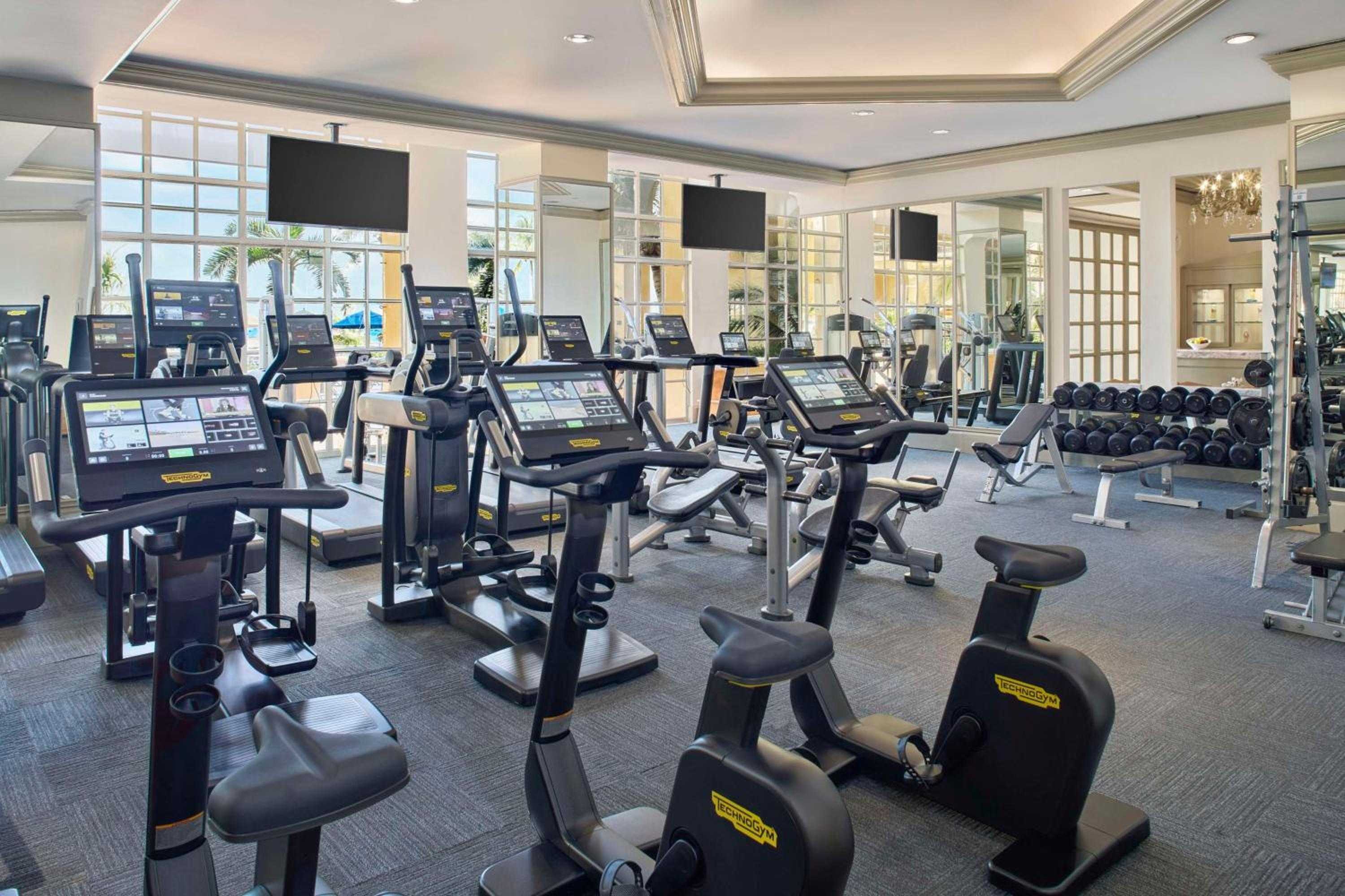 State-of-the-art TechnoGym equipment fills this bright, airy fitness center where floor-to-ceiling windows frame tropical views and gleaming surfaces reflect natural light.