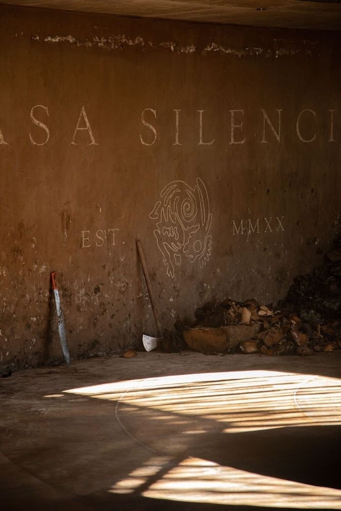 Sunlight streams across weathered concrete floors in the distillery's atmospheric tasting room, where rustic tools and aged walls tell stories of mezcal's ancient craft.