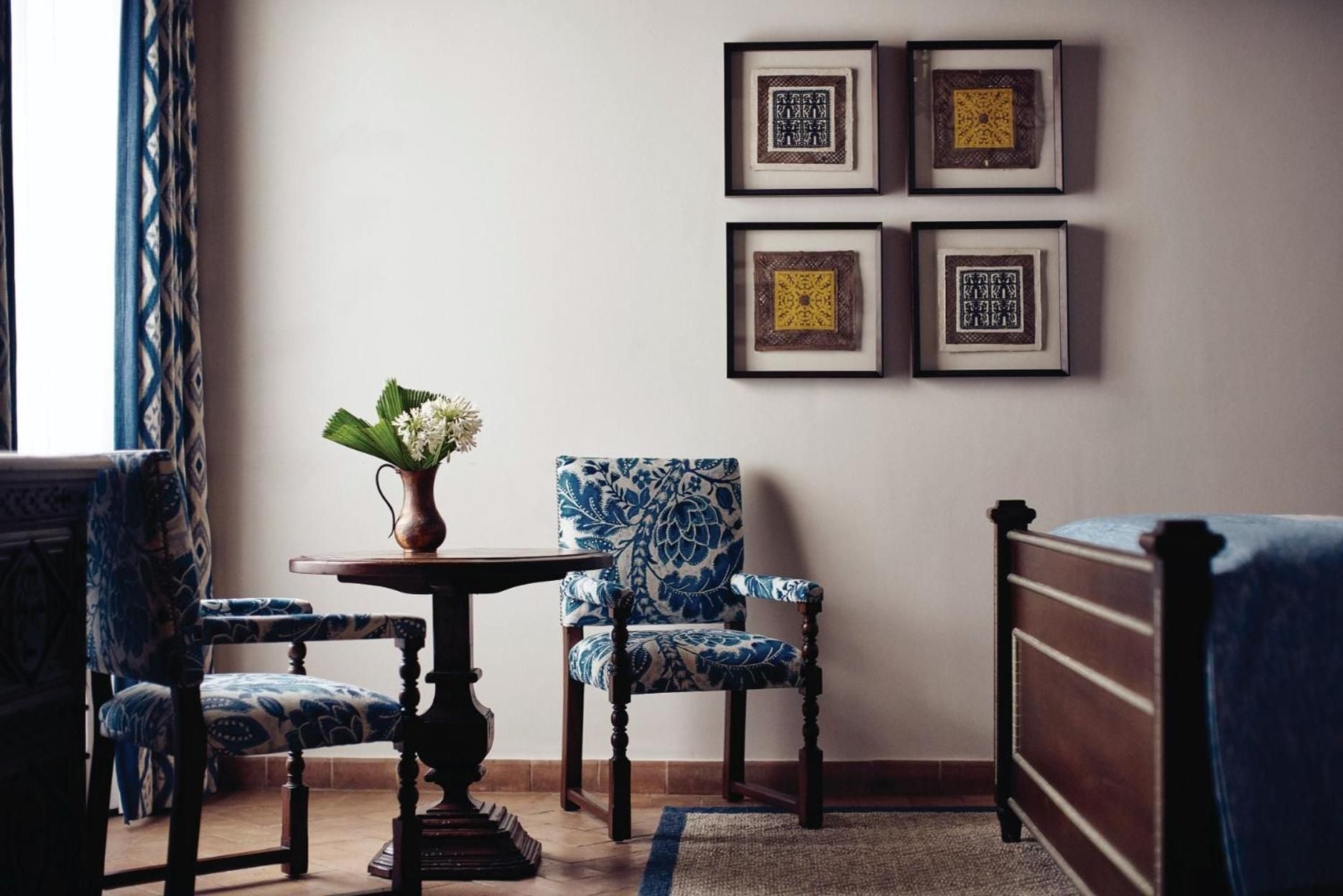 Blue and white textiles create an intimate sitting area where terracotta floors meet colonial charm, framed artwork adding sophisticated Mexican character.