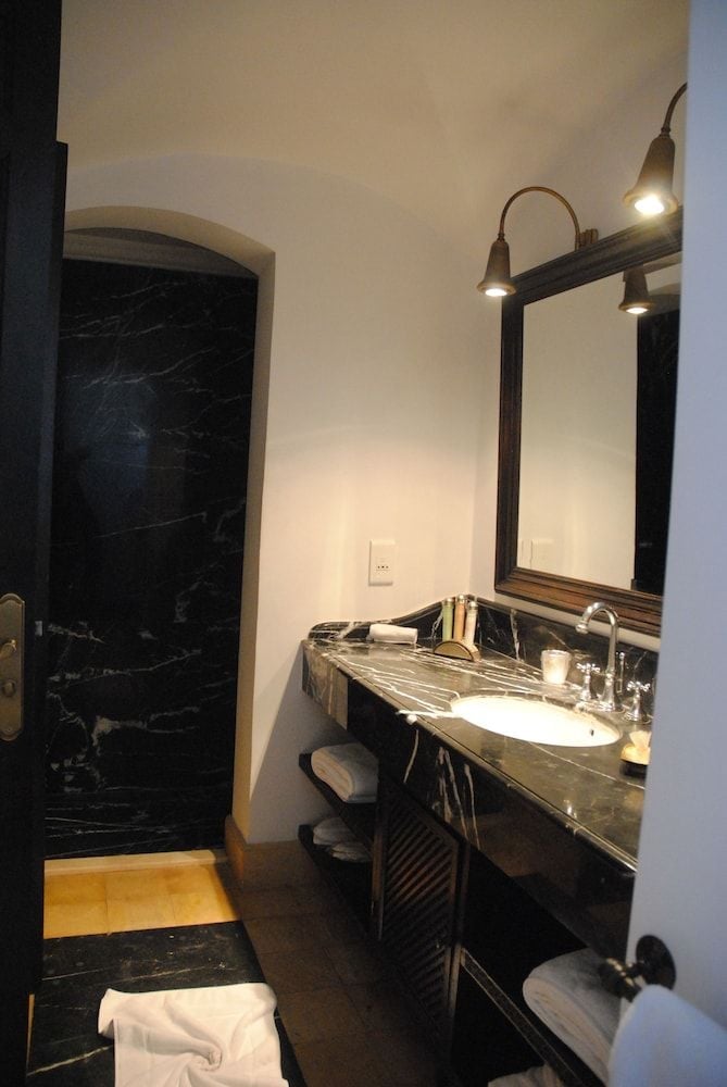 Dramatic black marble vanities and warm lighting create an intimate sanctuary where Moroccan craftsmanship meets contemporary luxury in this palatial bathroom retreat.