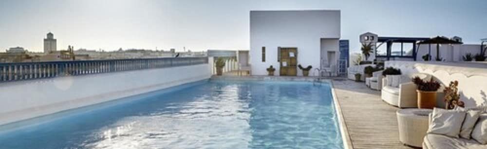 Infinity waters merge with Essaouira's ancient ramparts from this serene rooftop sanctuary, where Moroccan minimalism meets Atlantic horizons in perfect harmony.
