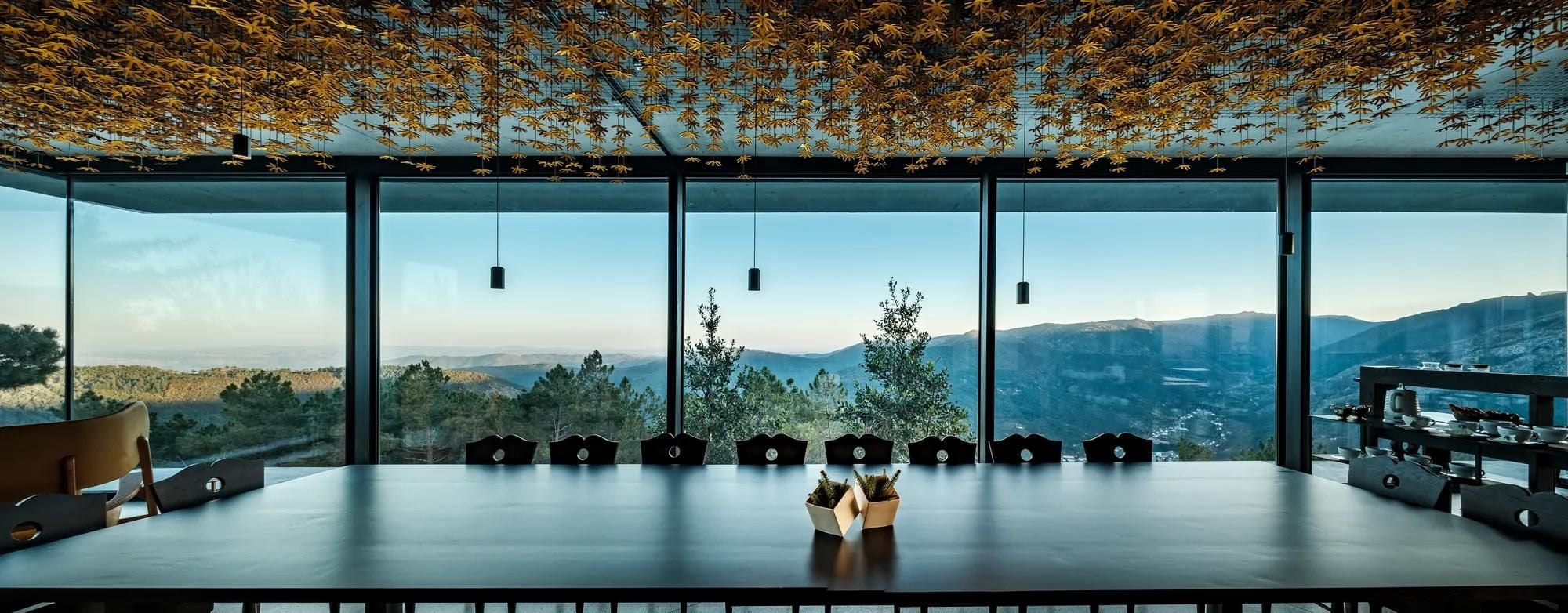 Floor-to-ceiling windows frame Portugal's Douro Valley while golden star-shaped installations create an intimate canopy above the dining table's sleek surface.