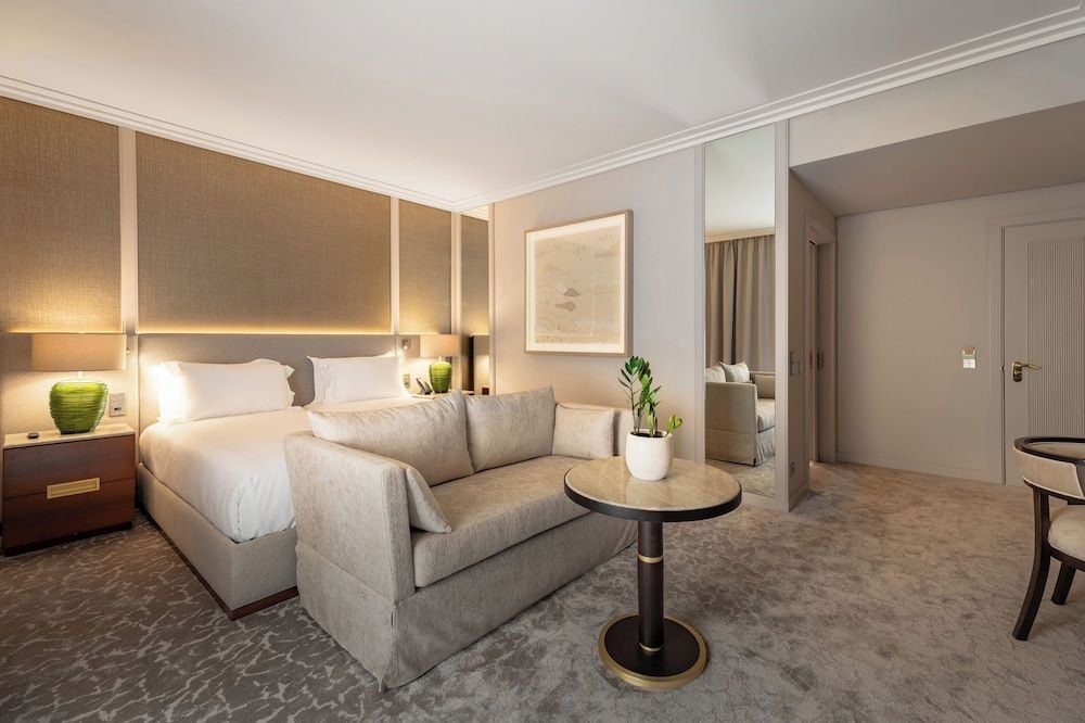 Warm wood paneling and soft ambient lighting create an intimate sanctuary, where plush seating invites lingering over morning coffee in this thoughtfully designed suite.