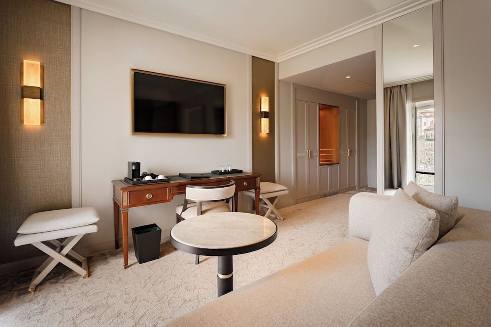 Warm wood tones and soft textures create an inviting sitting area where contemporary comfort meets classic Portuguese elegance in this thoughtfully appointed suite.