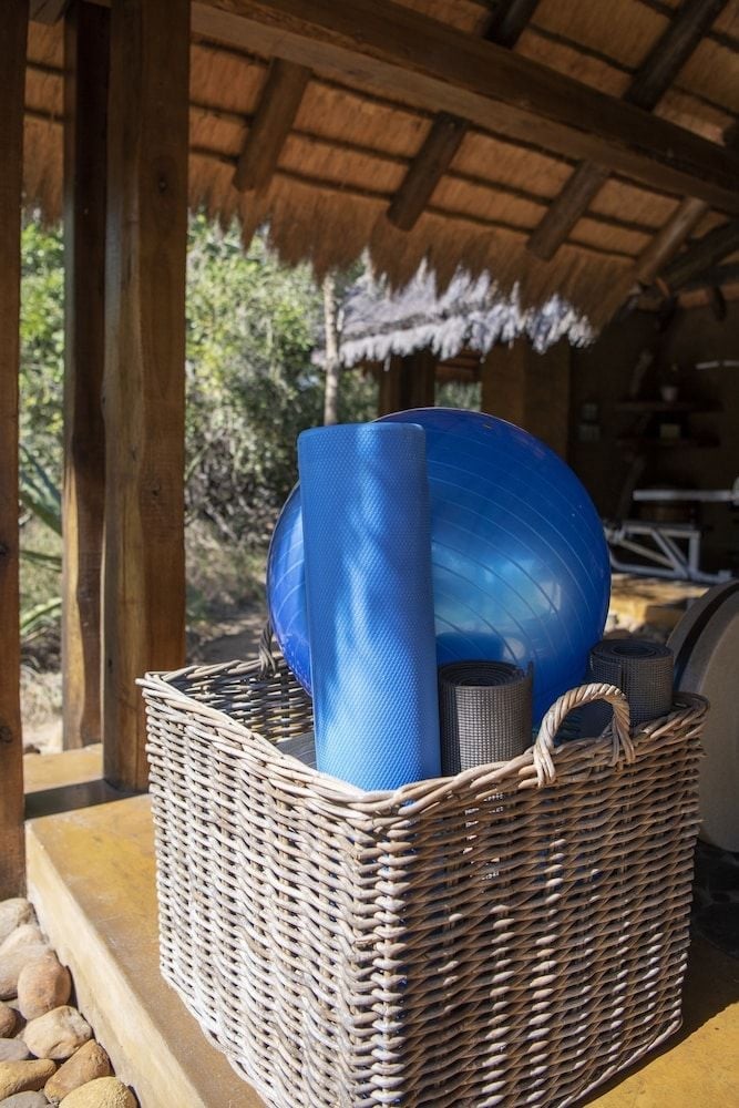 Woven baskets hold yoga mats and exercise balls beneath thatched eaves, where wellness meets wilderness in this thoughtfully designed safari retreat.