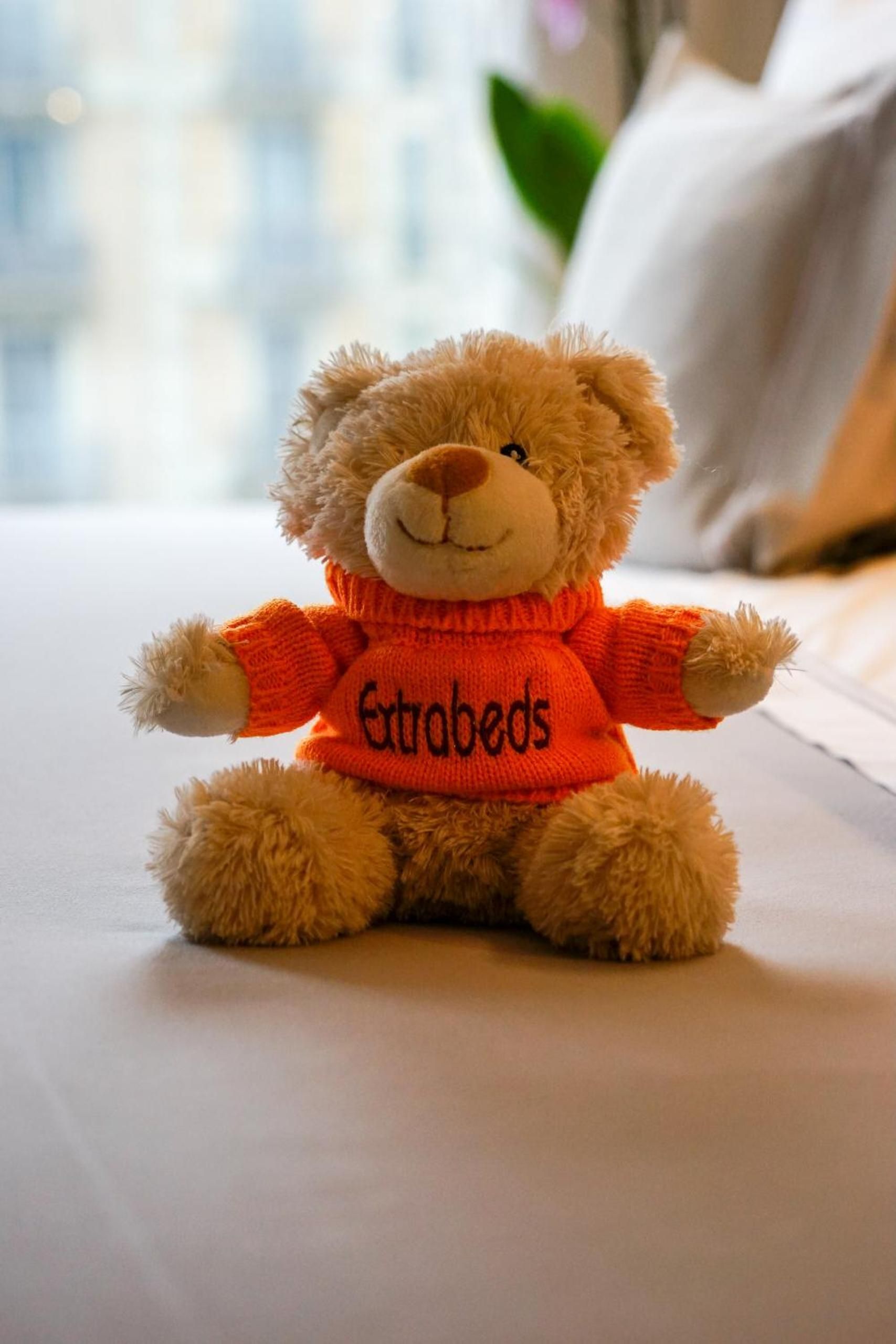 Thoughtful touches like this cheerful teddy bear in bright orange sweater create an unexpectedly warm, personalized welcome in guest quarters.