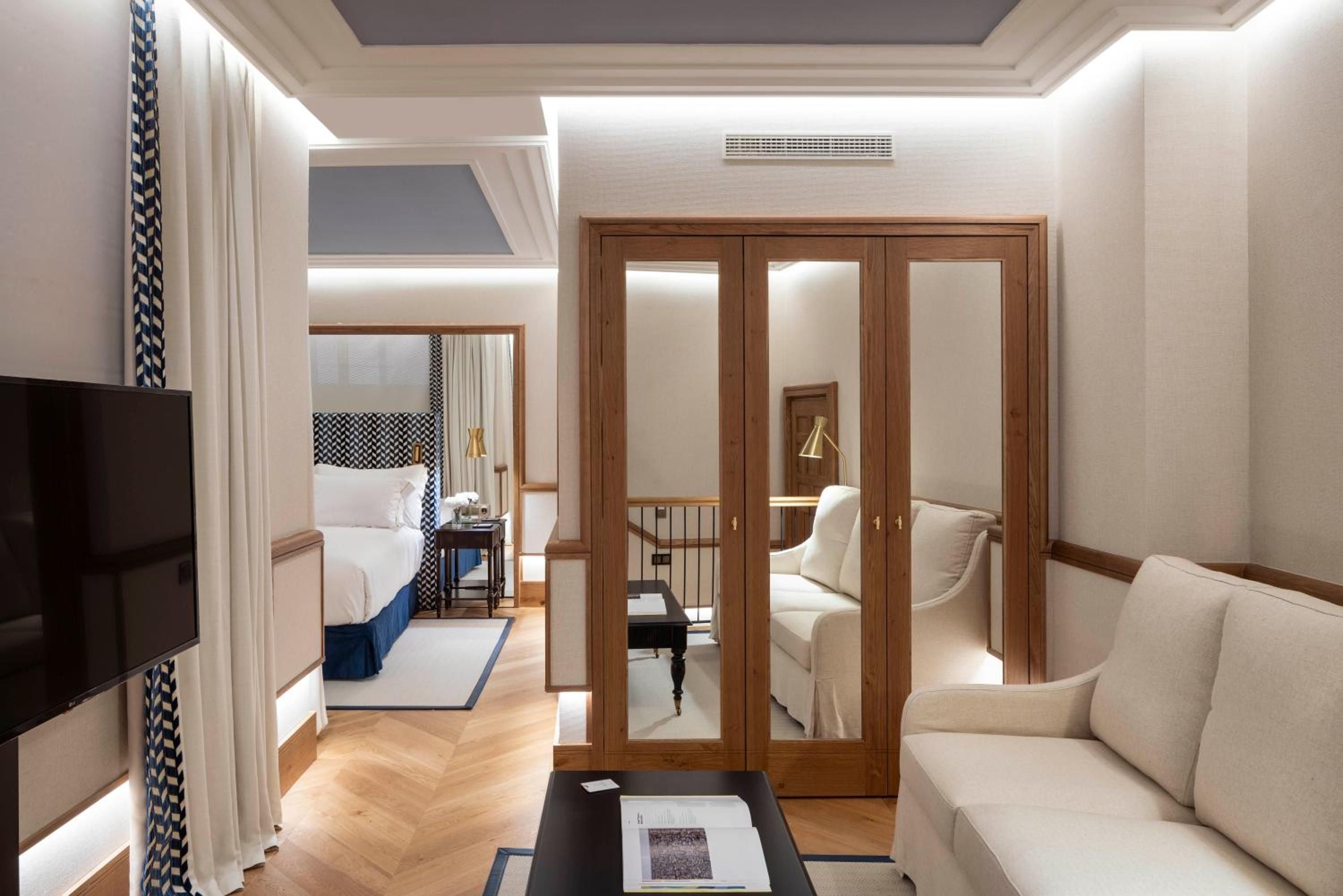 Warm wood-framed glass doors separate the living area from the bedroom, while chevron curtains and herringbone floors create sophisticated nautical elegance throughout this duplex suite.