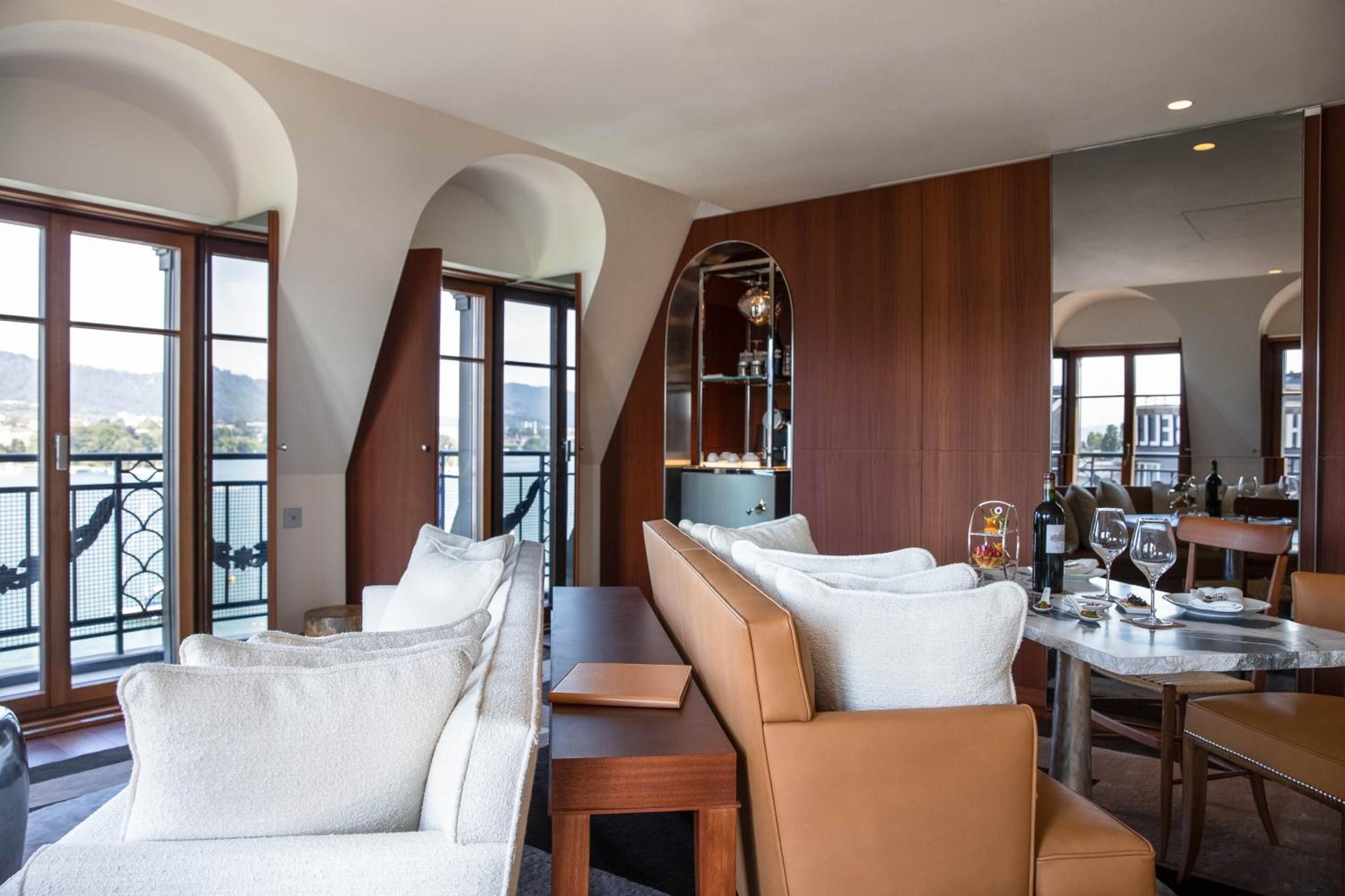 Curved archways frame Lake Zurich's serene waters while cognac leather and warm walnut create an intimate retreat where champagne moments unfold naturally.