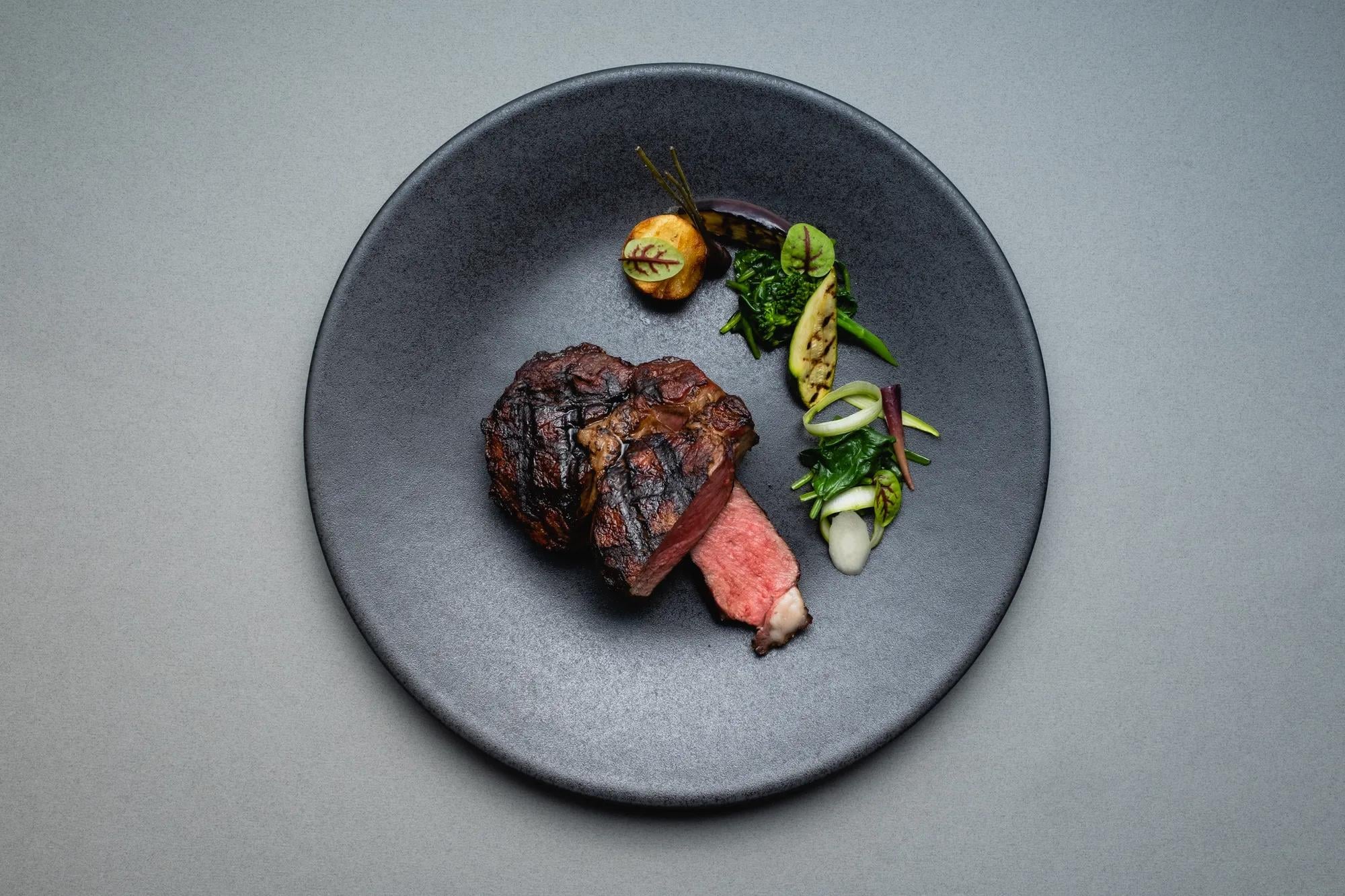 Perfectly seared beef reveals a blush-pink center, artfully plated with seasonal vegetables on handcrafted ceramic that reflects the hotel's commitment to culinary excellence.