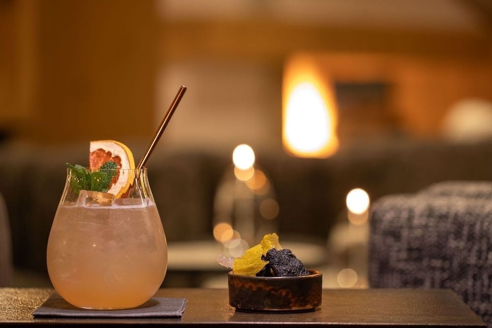 Warm candlelight illuminates craft cocktails garnished with fresh citrus and mint, while artisanal caviar service adds an intimate luxury to evening hours.