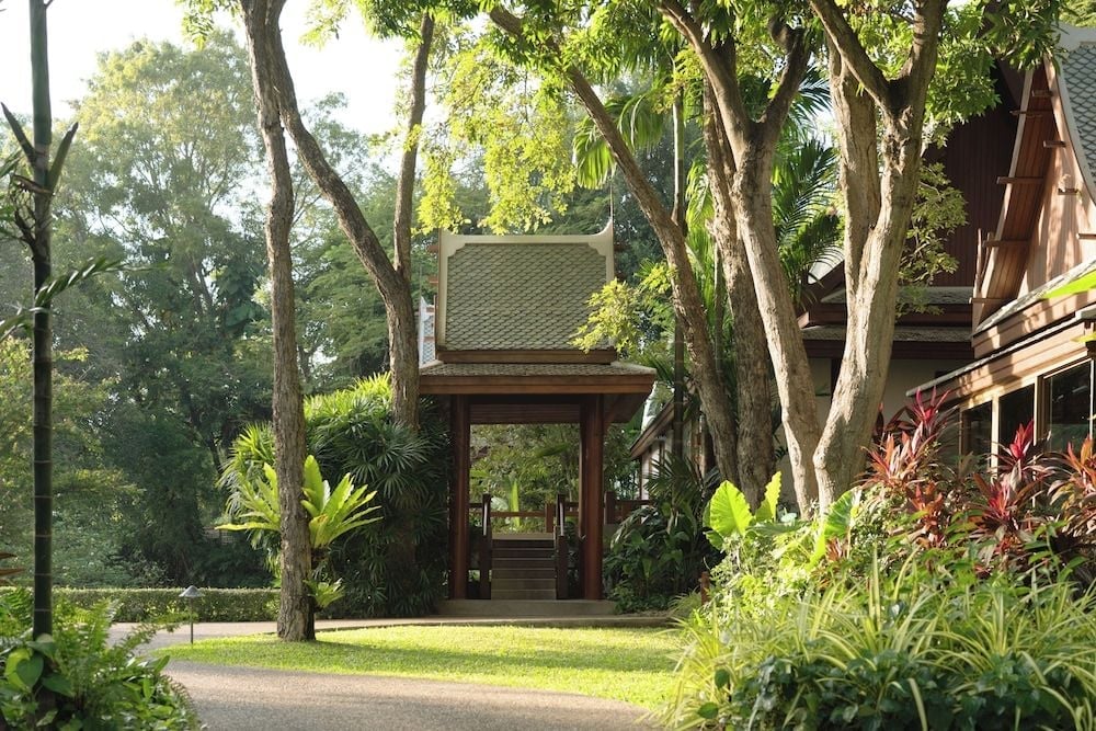 Traditional Thai pavilions emerge through tropical canopies, their peaked roofs and timber frames creating intimate sanctuaries amid Chiva-Som's verdant wellness grounds.