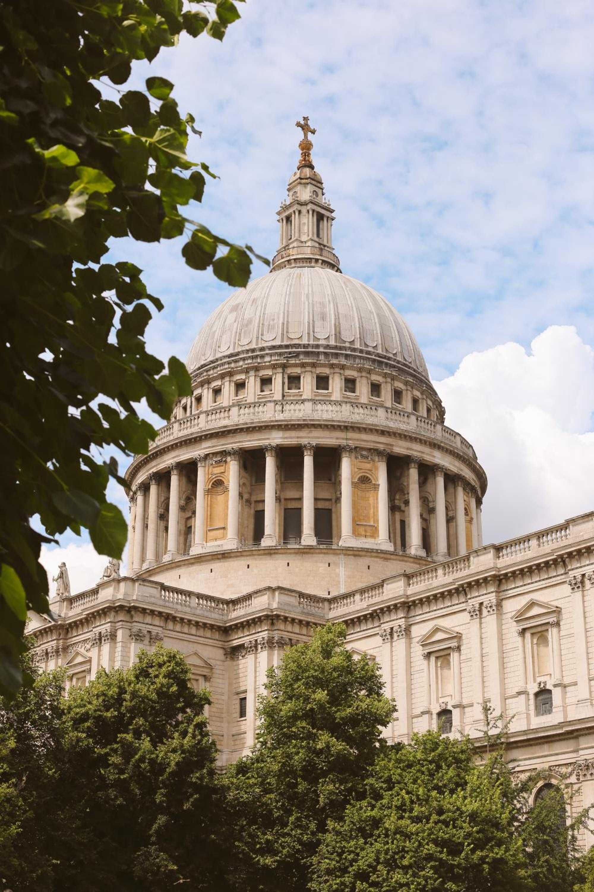 St. Paul's Cathedral's iconic dome rises majestically through verdant London plane trees, its baroque grandeur commanding the cityscape just steps from The Ned's banking hall doors.