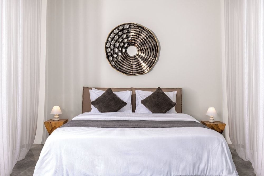 Crisp white linens and charcoal accents create serene sophistication, while the sculptural wall art adds artistic flair to this minimalist sanctuary.