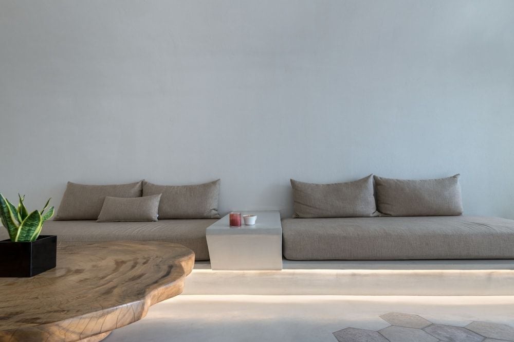 Floating platforms of warm wood and illuminated marble create serene seating nooks, where minimalist gray cushions invite lingering conversations over candlelit moments.