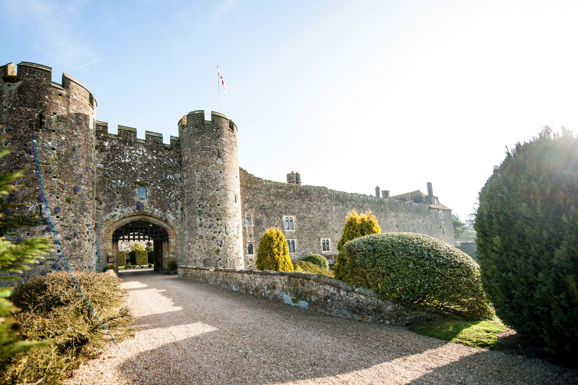 Stone towers and crenellated walls rise majestically from manicured topiary gardens, where centuries-old battlements meet perfectly sculpted hedgerows in timeless harmony.