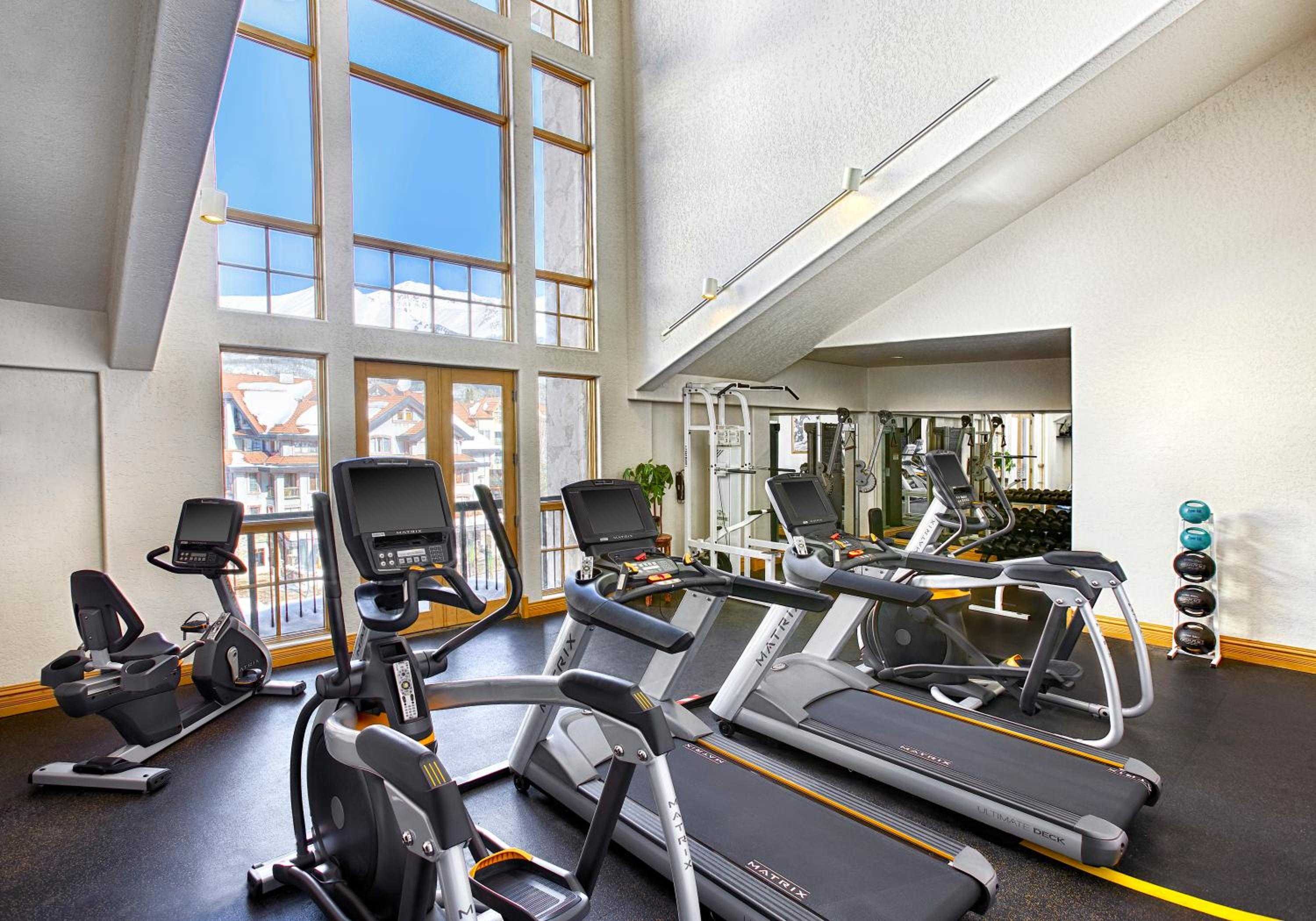 Floor-to-ceiling windows frame Alpine vistas while state-of-the-art cardio equipment creates an inspiring workout space where mountain peaks motivate every stride.