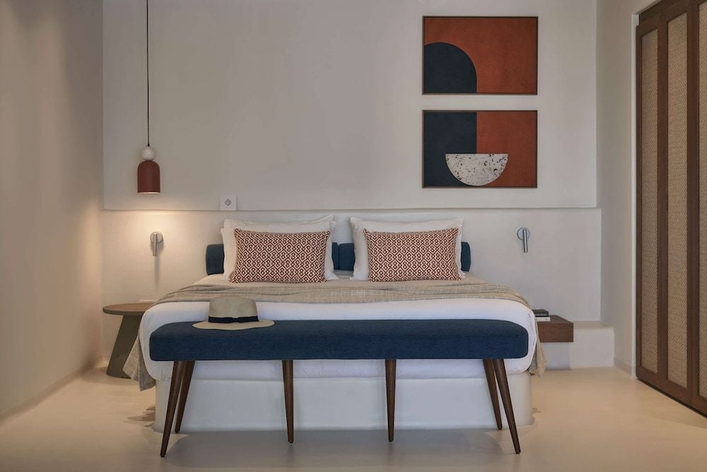 Clean lines and earthy tones define this sophisticated suite, where geometric artwork complements warm terracotta pendant lighting and rich navy accents against crisp white linens.