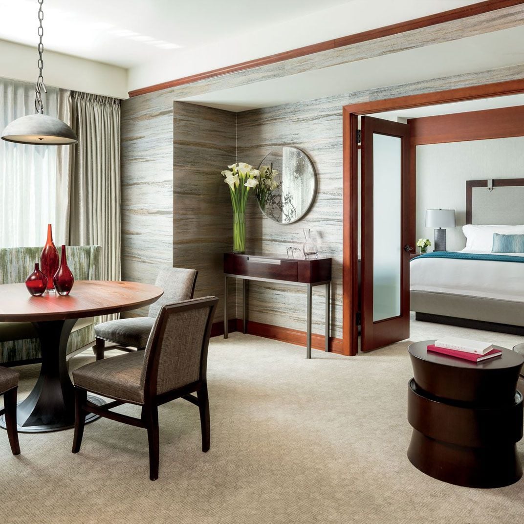 Rich mahogany frames and textured stone walls create an intimate dining nook, where pendant lighting casts a warm glow over polished surfaces and contemporary furnishings.