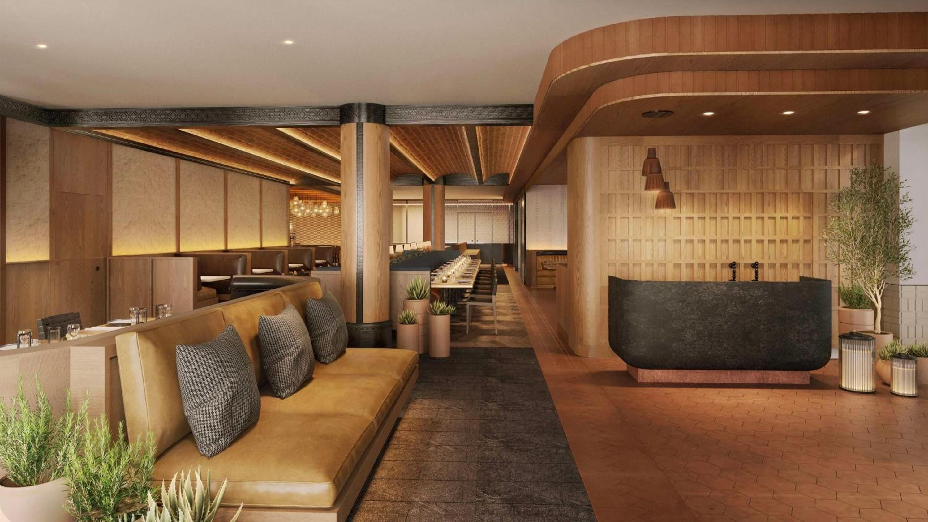 Warm wood tones and curved ceiling details create an inviting flow through the lobby, where contemporary furnishings blend seamlessly with biophilic design elements.