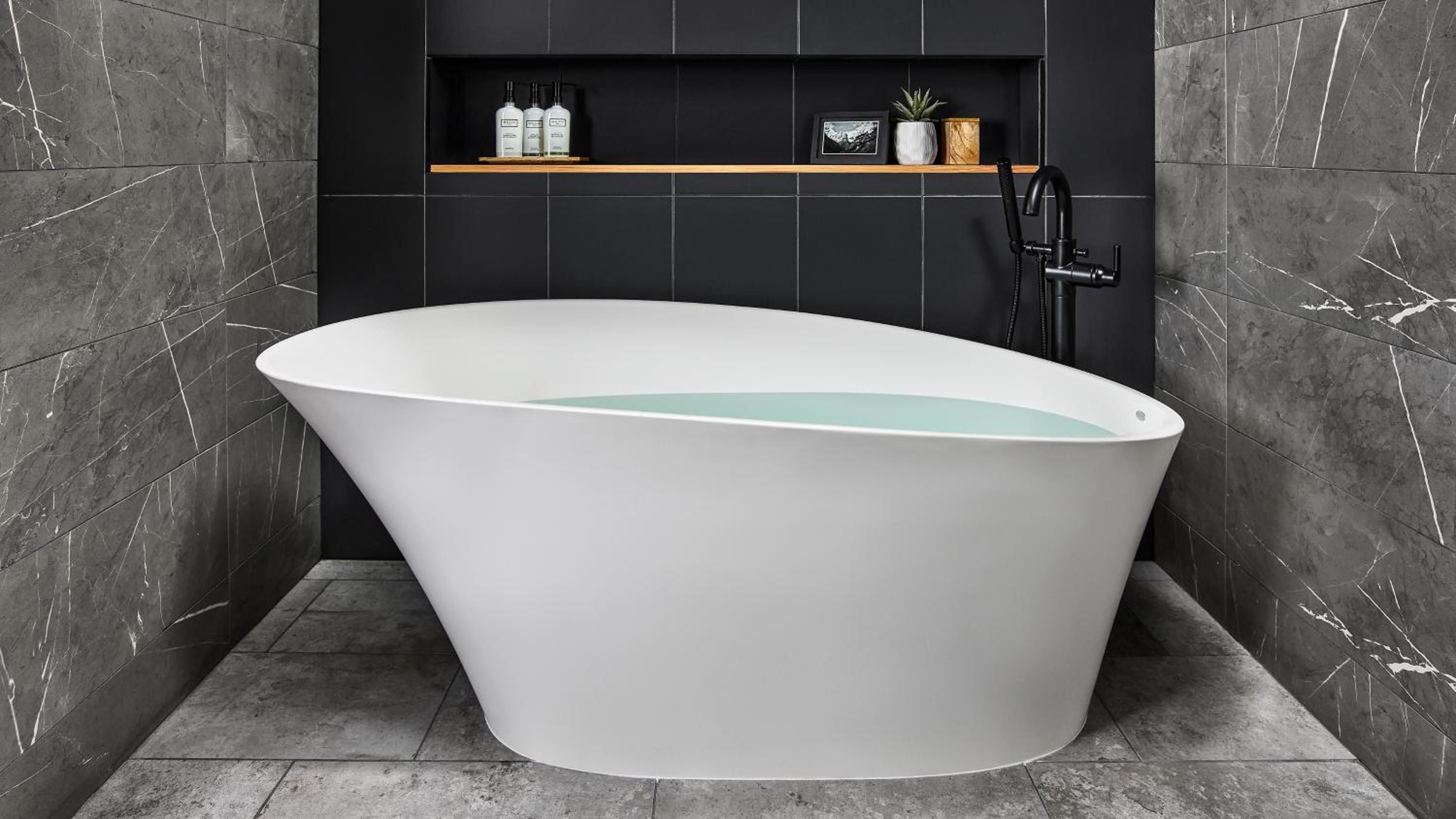 Sleek marble veining frames a sculptural soaking tub where modern luxury meets spa-like tranquility, complete with curated amenities and warm wood accents.