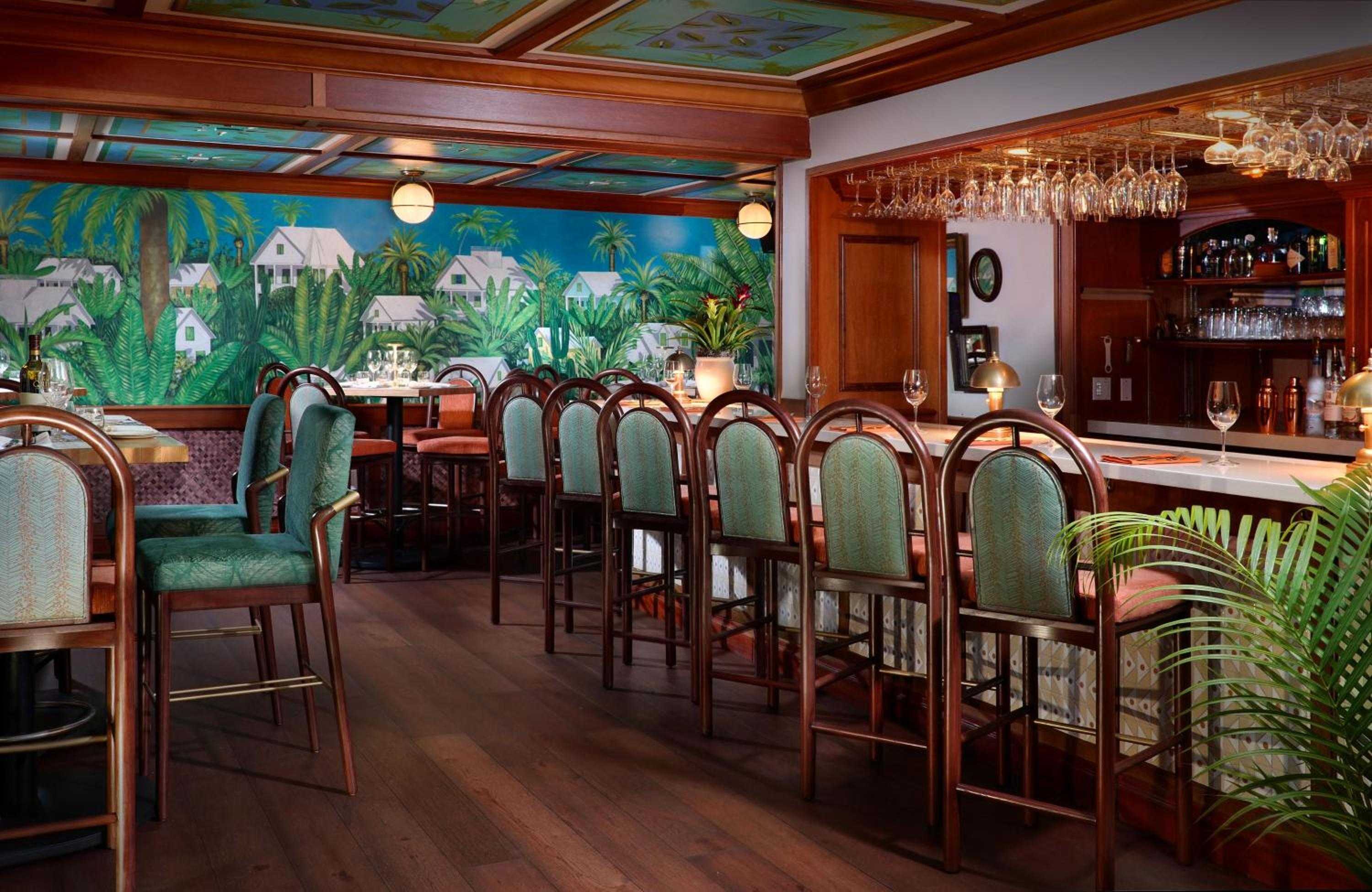 Tropical murals and gleaming mahogany create an inviting island atmosphere where craft cocktails and conversation flow beneath hand-painted palm fronds and exposed wooden beams.