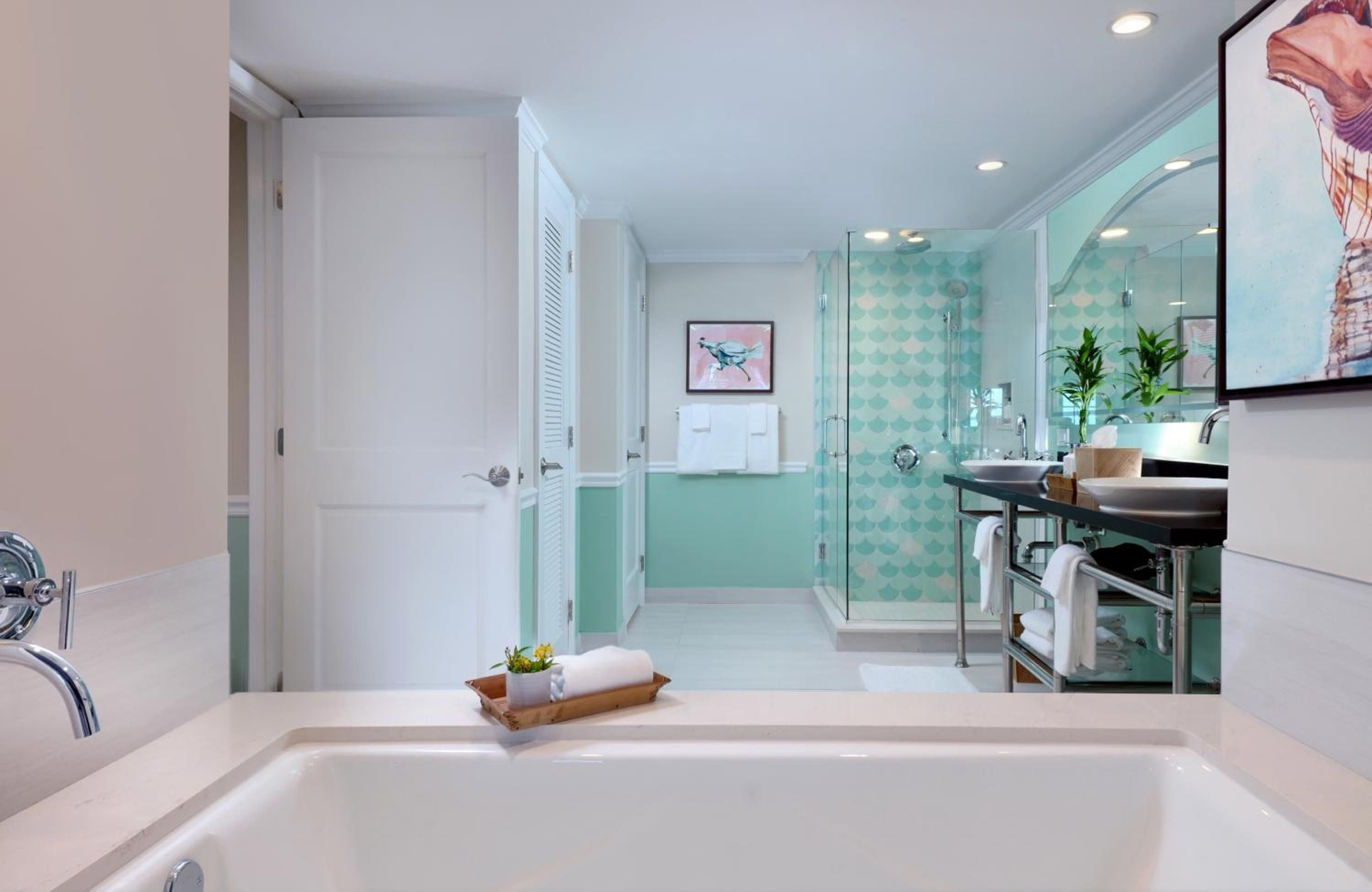 Seafoam-tiled shower walls and sleek vessel sinks create a spa-like sanctuary where morning light filters through plantation shutters onto polished surfaces.