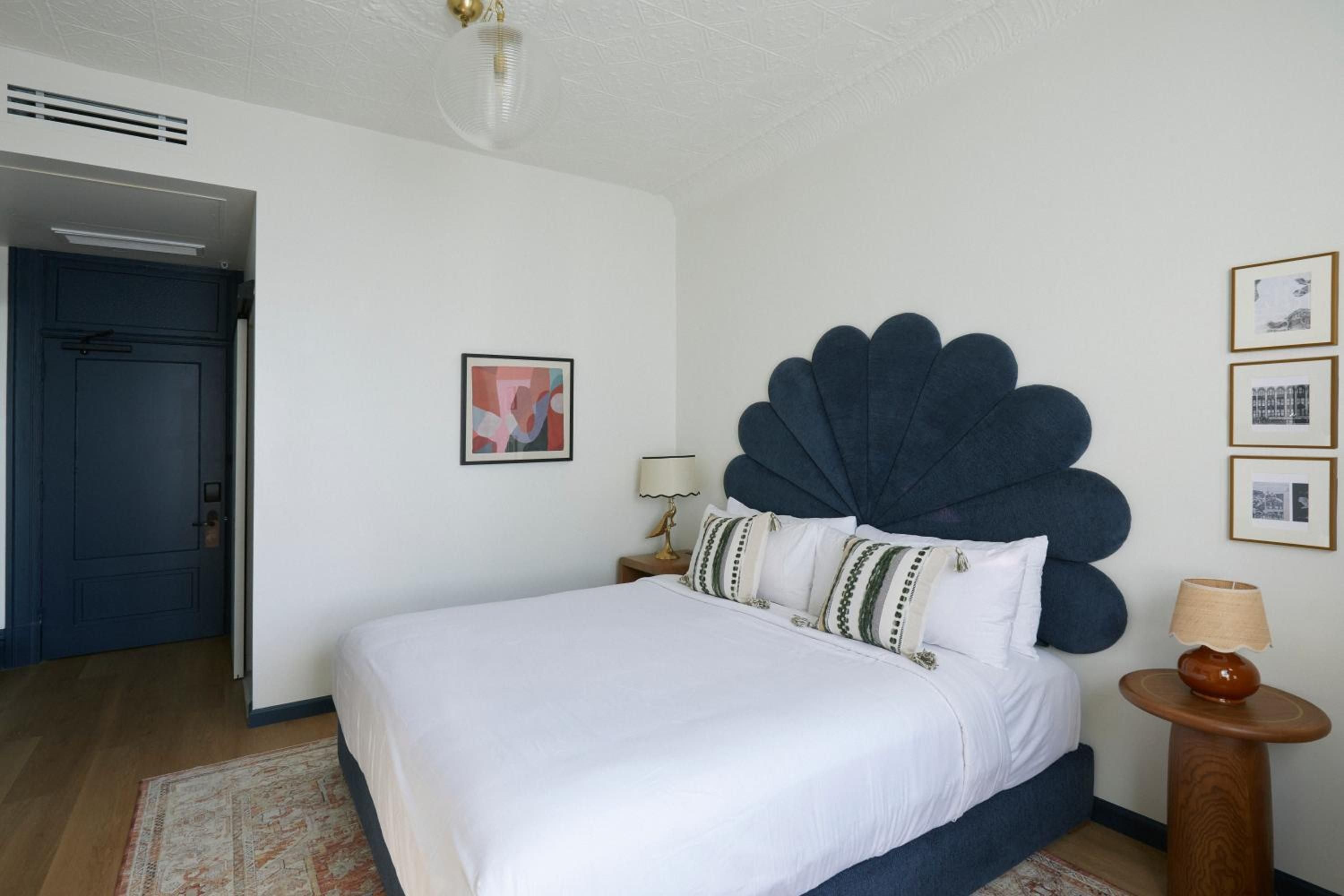 Navy scalloped headboards create dramatic focal points against crisp white linens, while thoughtfully curated artwork and warm wood accents add sophisticated charm to each guest room.