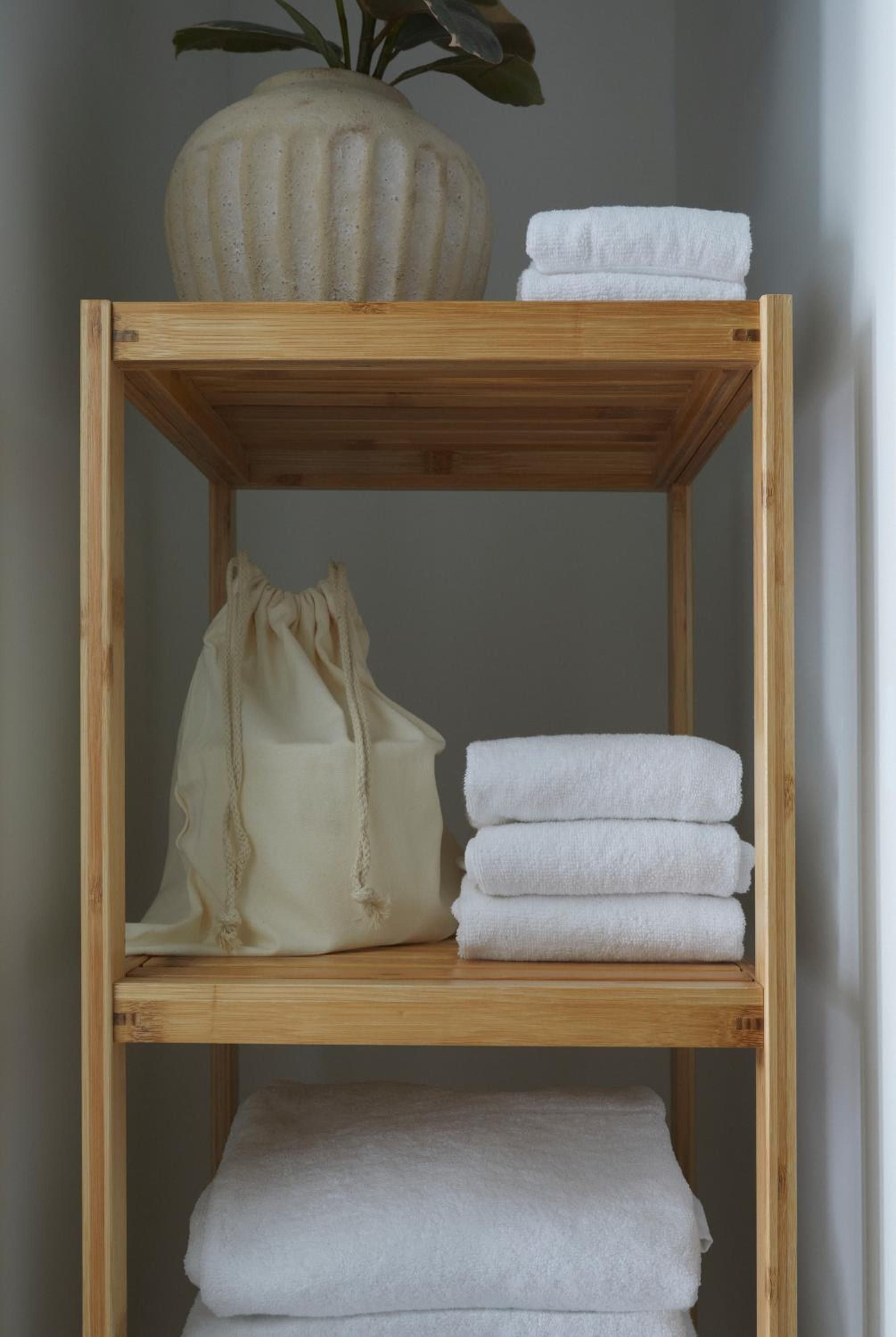 Organic textures meet minimalist design in thoughtfully curated bathroom storage, where neatly folded linens and natural materials create a serene, spa-like sanctuary.