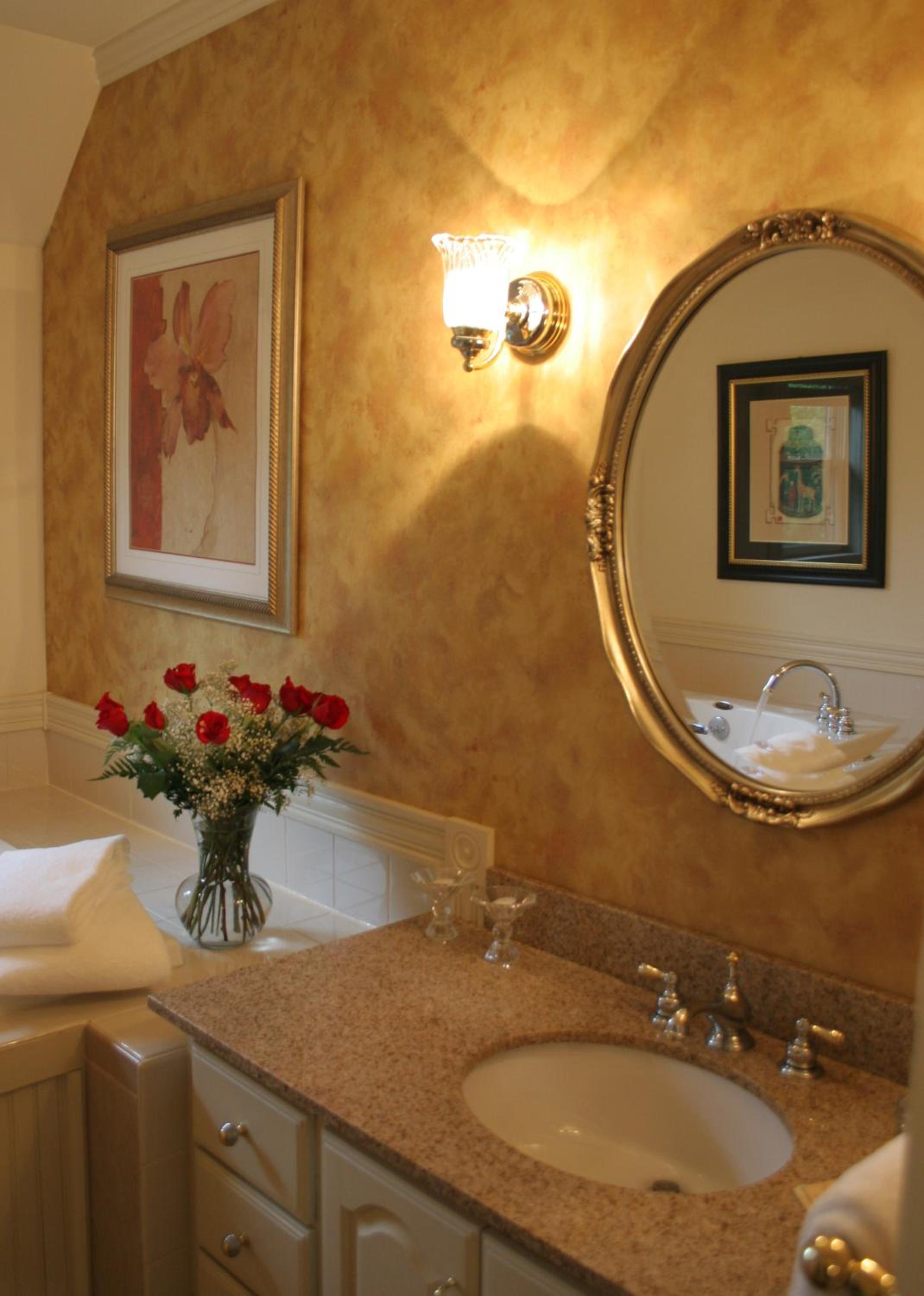 Golden-hued walls embrace polished granite and gleaming fixtures, while fresh roses add romance to this intimate powder room's warm, residential elegance.