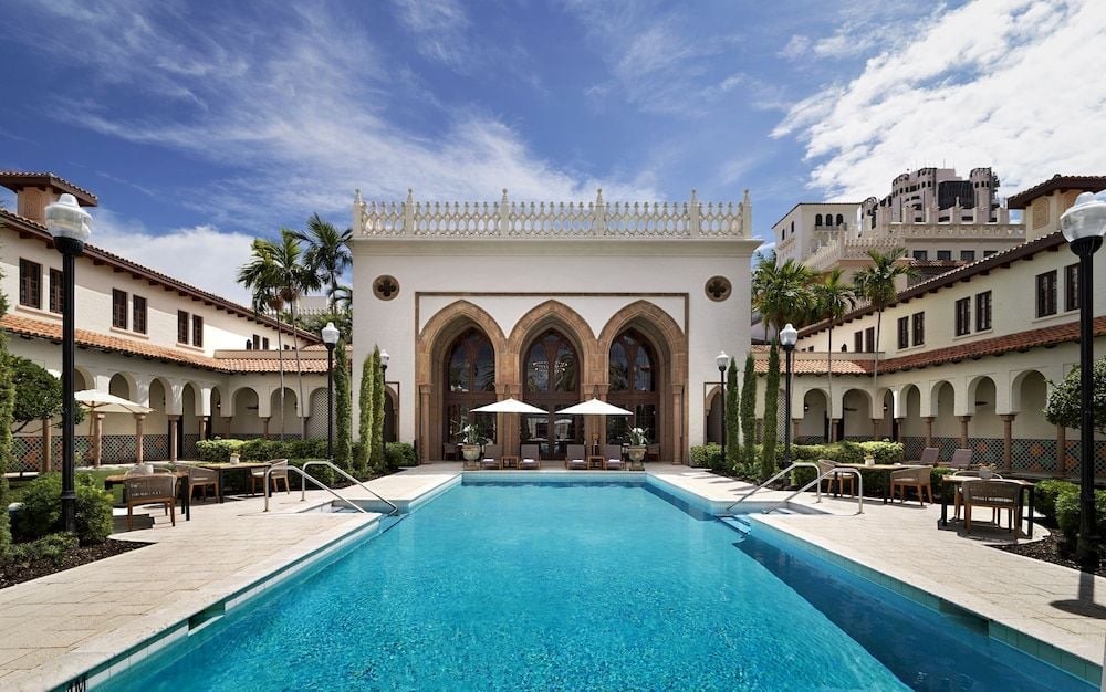Moorish arches frame a serene courtyard pool where Mediterranean elegance meets Florida sunshine, creating an intimate oasis within the resort's sophisticated embrace.