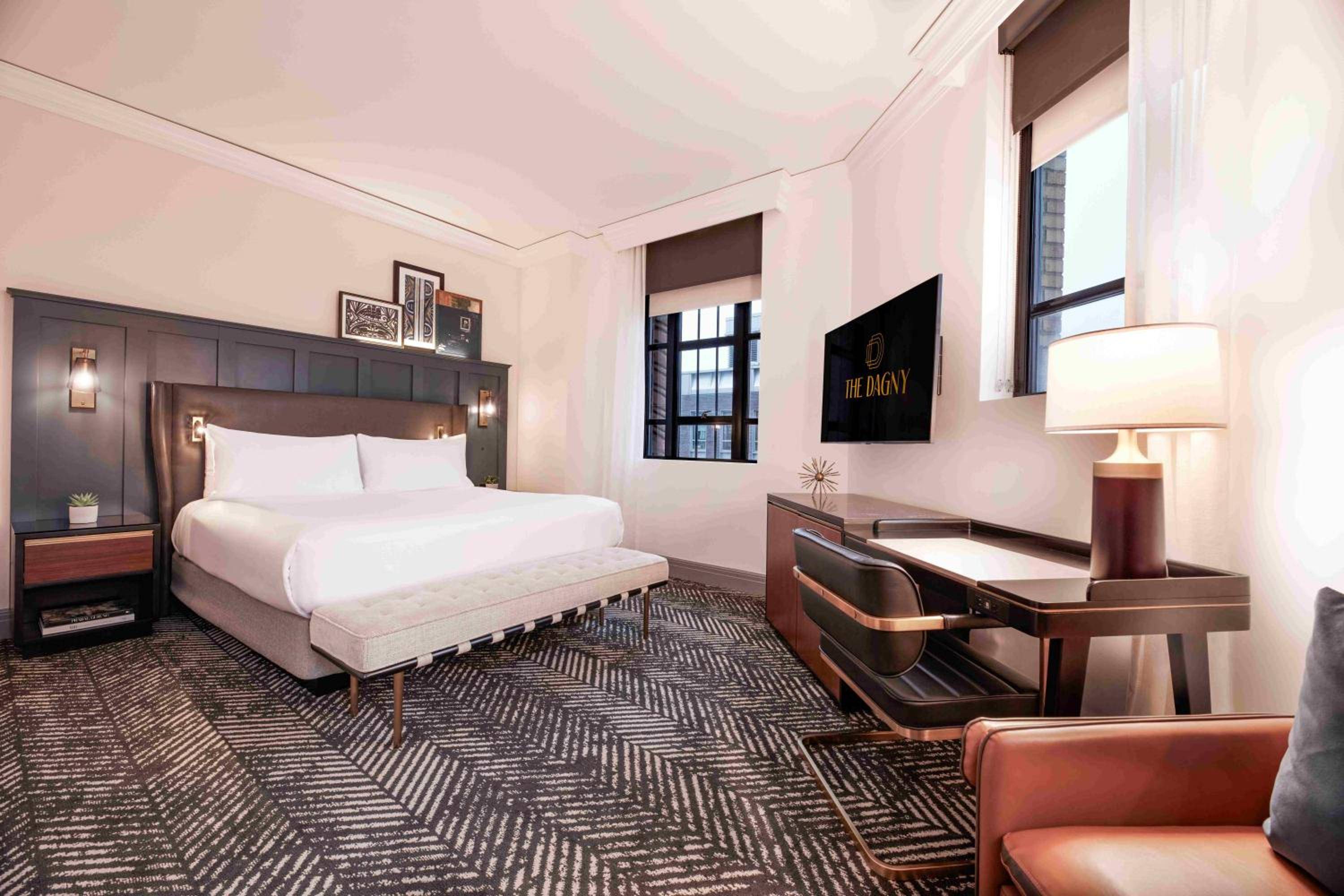 Warm wood tones and geometric carpeting create an inviting retreat, where thoughtful lighting and mid-century furnishings blur the line between boutique hotel and urban sanctuary.