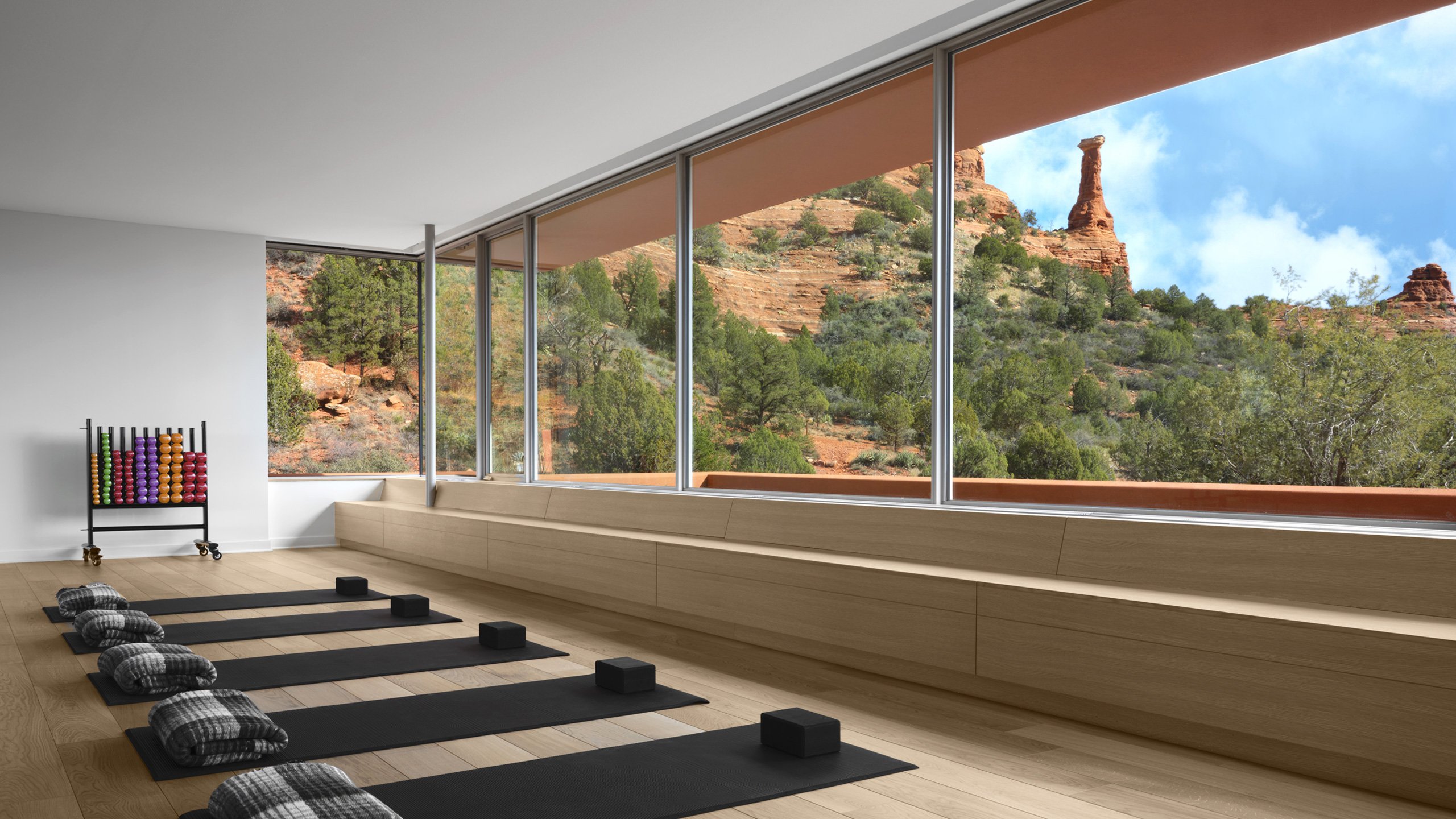 Yoga mats await beneath soaring windows that frame Sedona's crimson cliffs, where meditation meets the raw beauty of Arizona's red rock country.