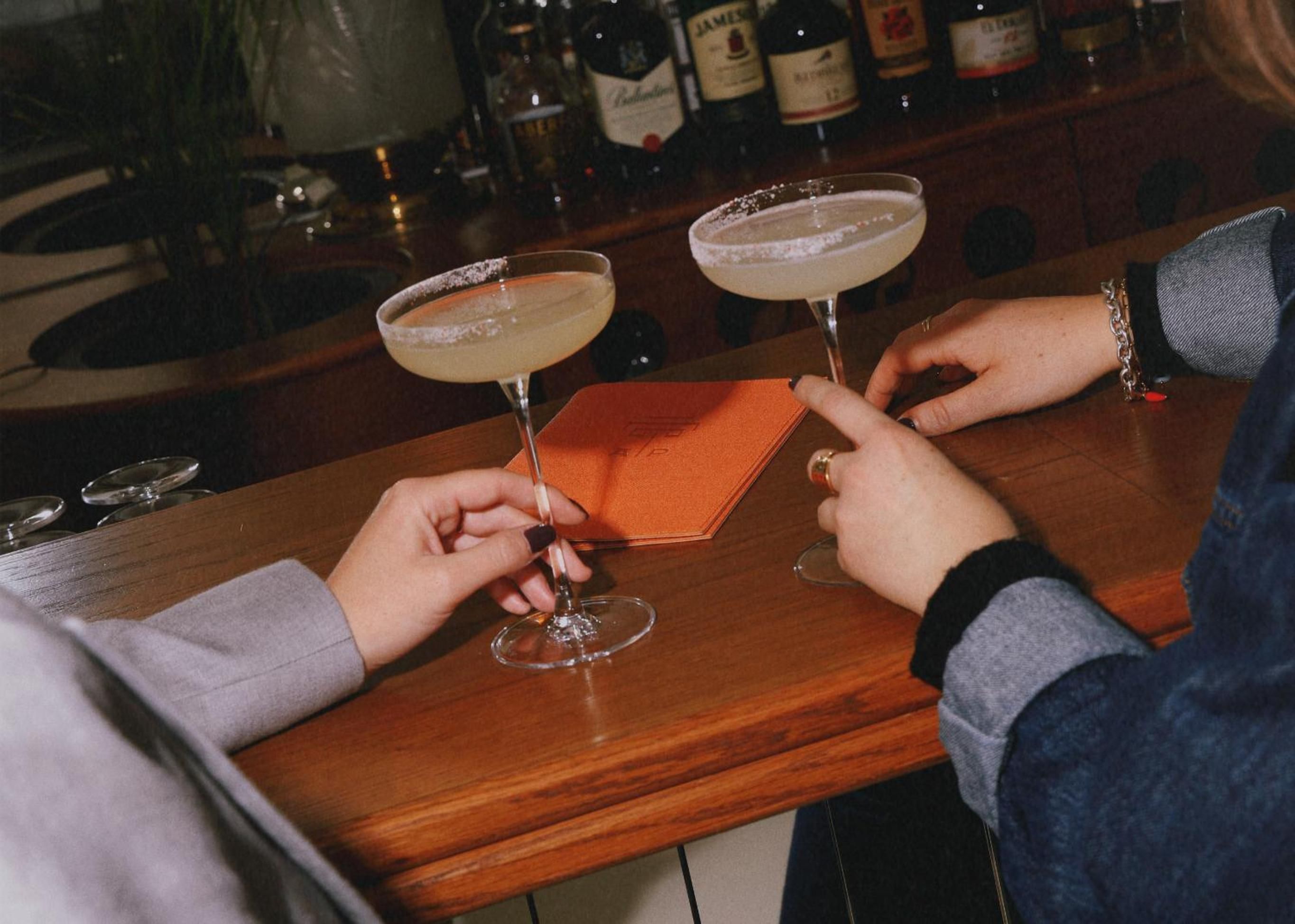 Salt-rimmed cocktails catch amber light at the intimate bar, where skilled hands craft perfect margaritas against a backdrop of premium spirits.
