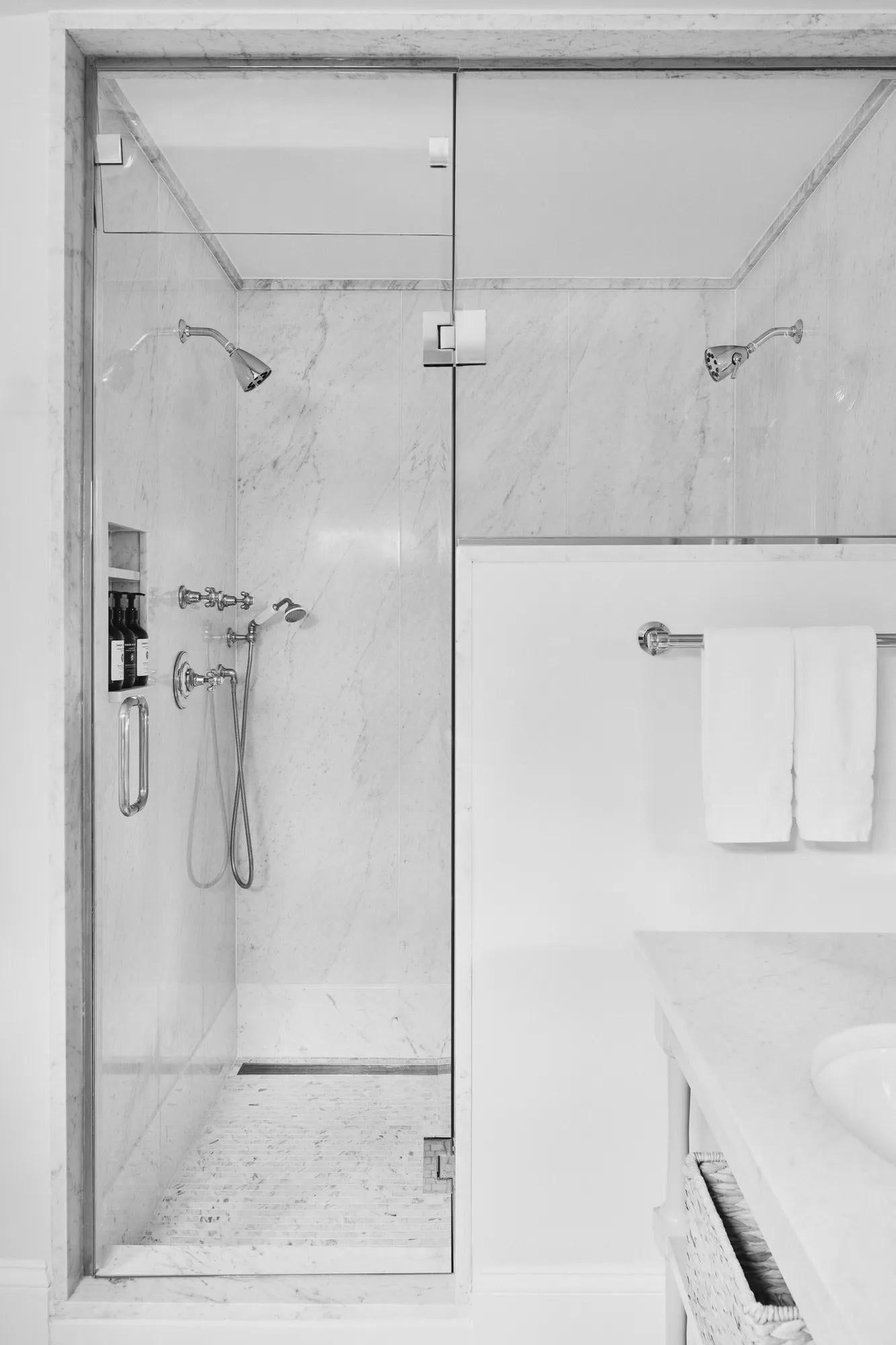 Carrara marble envelops this spa-like shower sanctuary, where polished chrome fixtures and clean geometric lines create a temple of modern luxury.