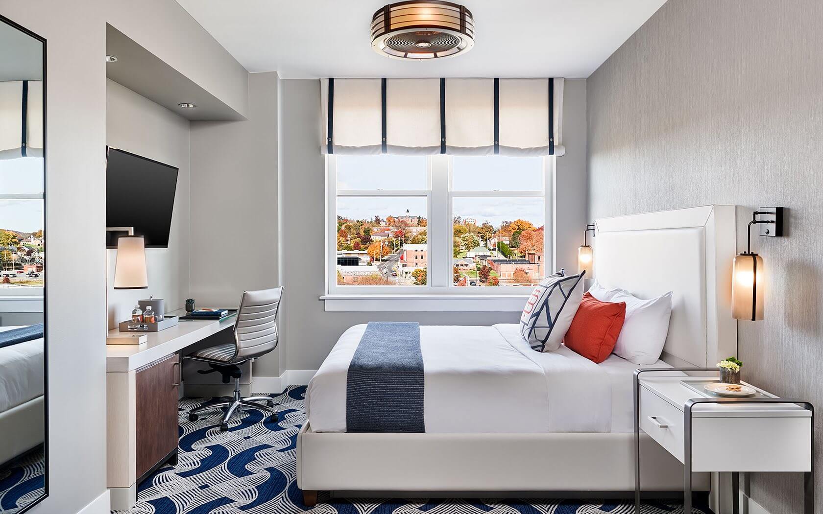Contemporary guest rooms blend nautical-inspired carpeting with clean lines, while oversized windows frame autumn views of the surrounding New England neighborhood.
