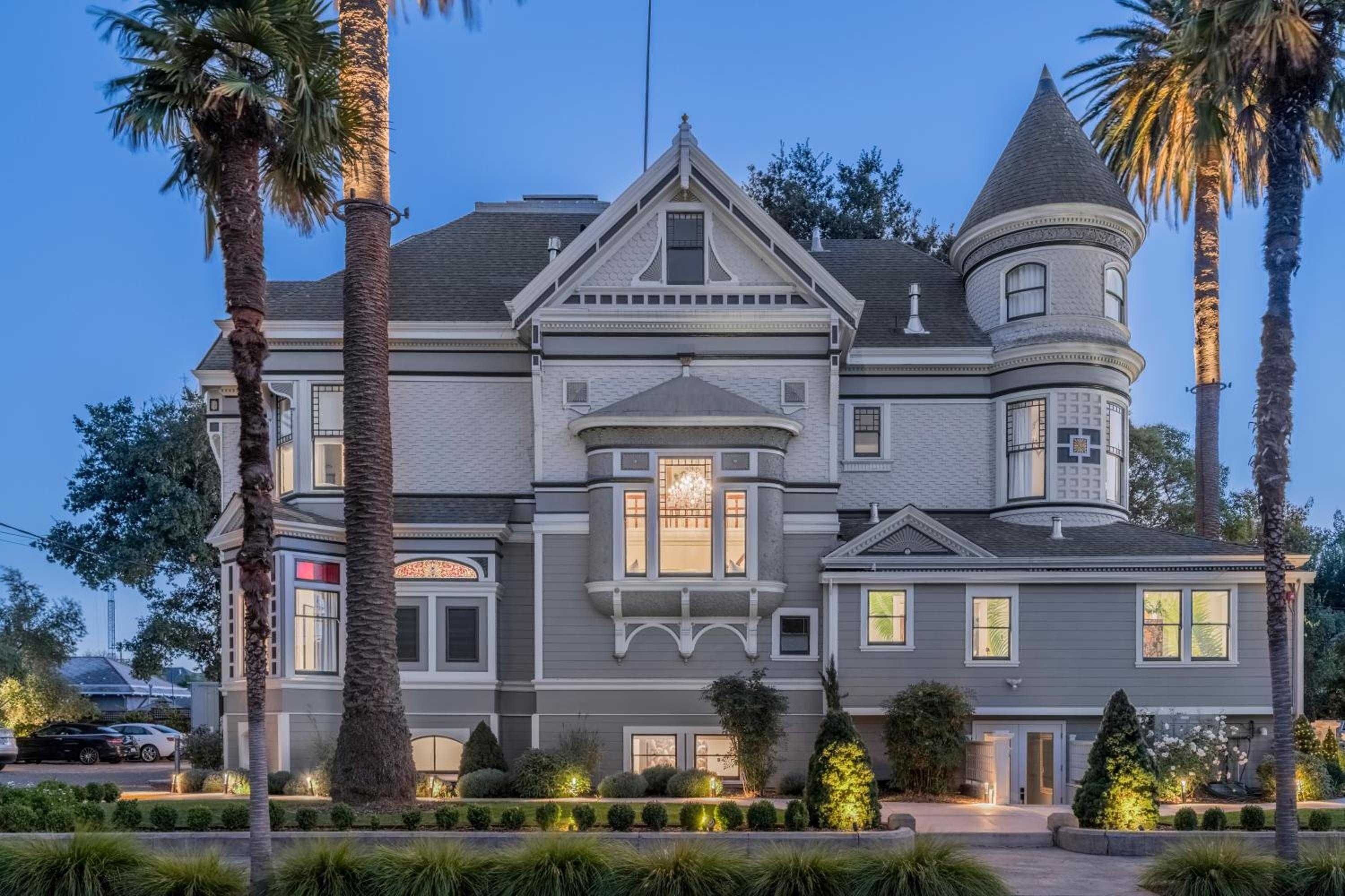Victorian grandeur meets California charm in this meticulously restored mansion, where turrets and gables create dramatic silhouettes against twilight skies framed by swaying palms.