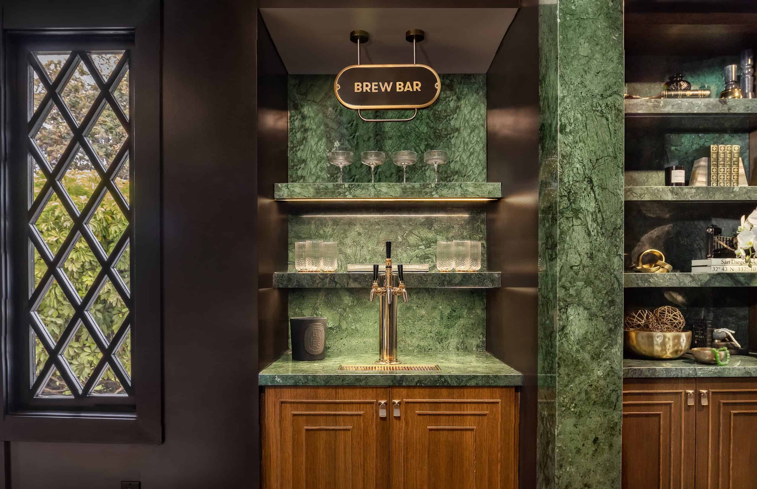 Green marble envelops the intimate brew bar, where brass taps gleam beneath warm pendant lighting and crystal glassware awaits the perfect pour.