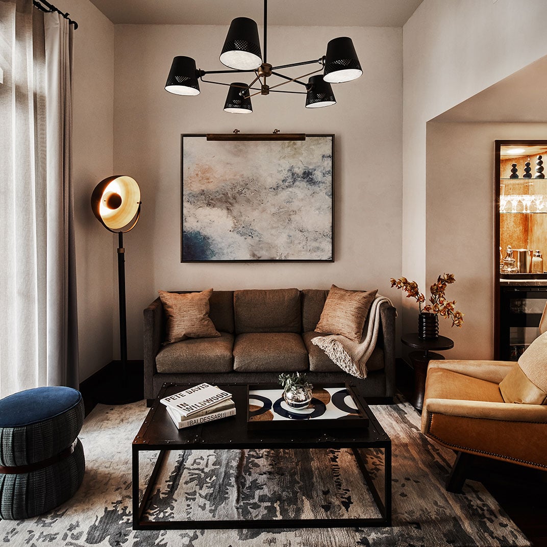 Warm earth tones and industrial-chic lighting create an intimate living space where abstract art anchors cozy seating and thoughtfully curated design details.