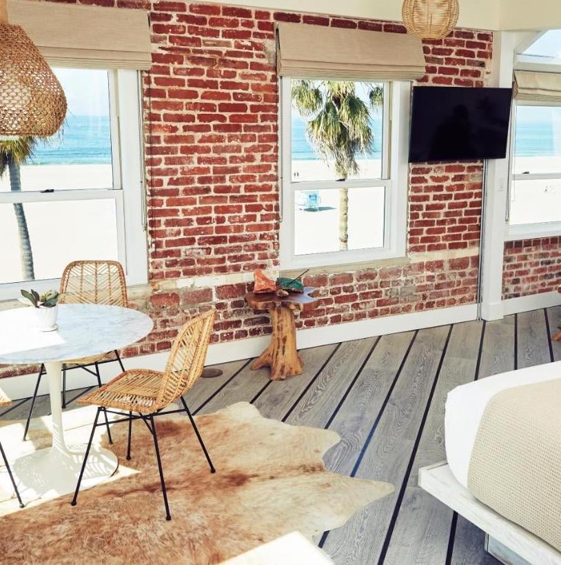 Exposed brick walls and woven pendant lights frame ocean vistas in this coastal retreat, where natural textures meet weathered wood floors and rattan seating.