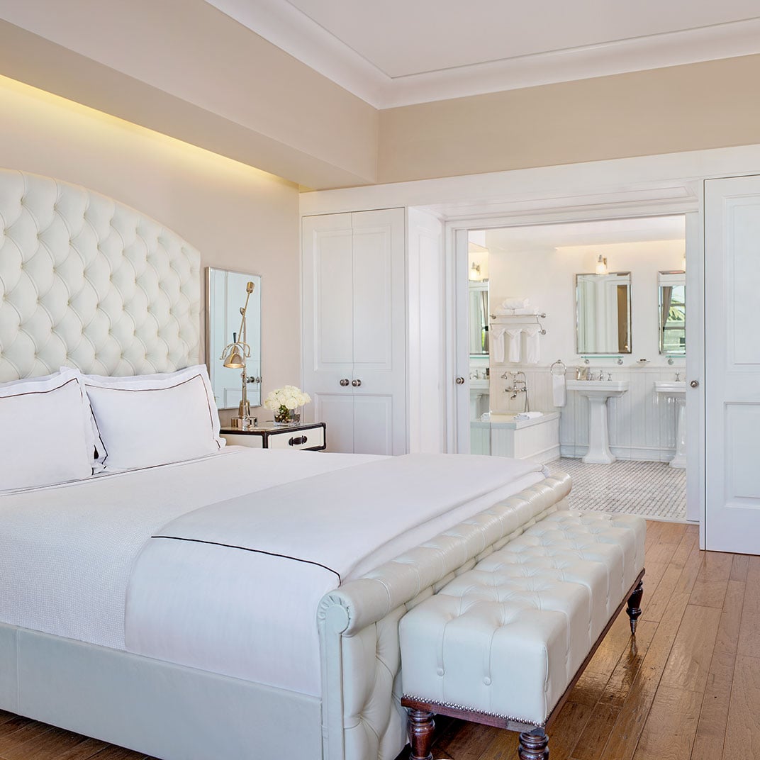 Tufted white headboards and marble-clad en-suite bathrooms create an airy sanctuary where classic elegance meets contemporary comfort in every thoughtfully appointed detail.
