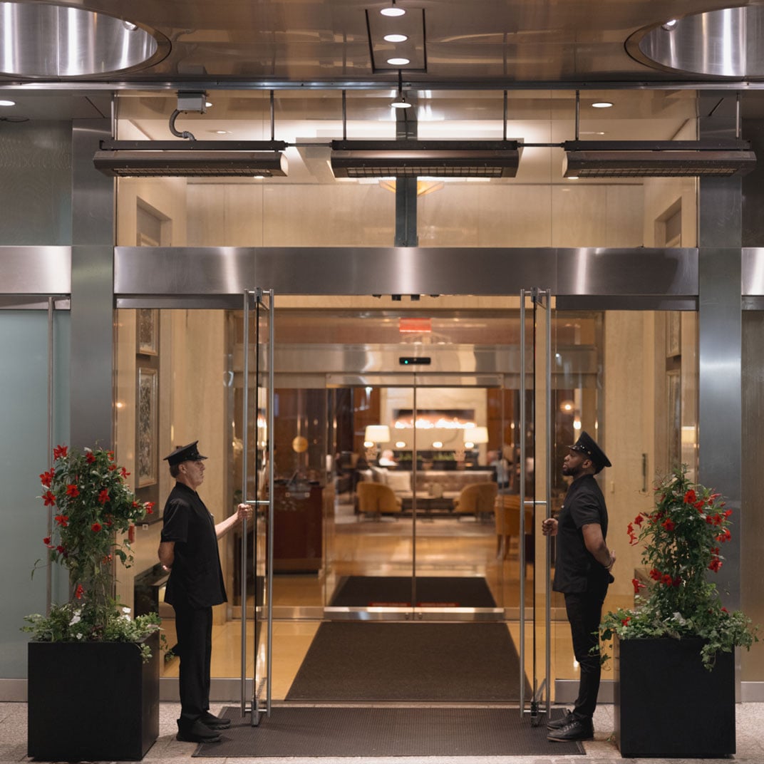 Uniformed doormen stand sentinel at gleaming glass doors, where polished marble floors and fresh florals create an atmosphere of effortless sophistication and old-world service.