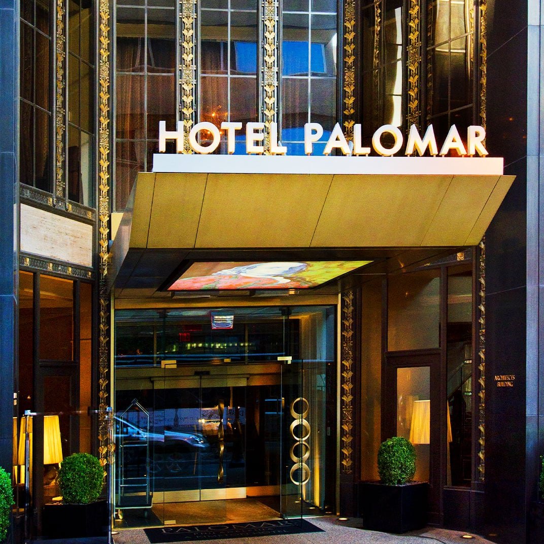 Art Deco glamour meets modern sophistication at this striking downtown entrance, where golden ornamental details frame glass doors beneath bold illuminated signage.