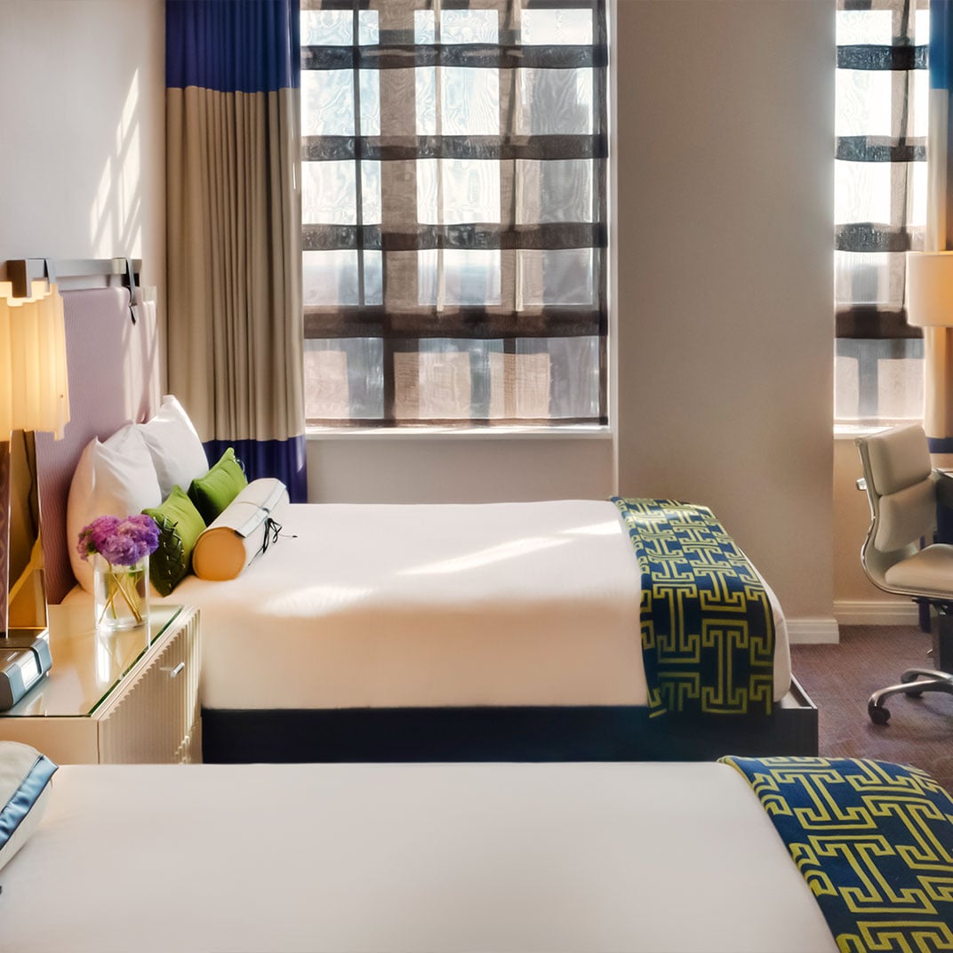 Crisp white linens meet bold geometric runners in navy and gold, while soft lamplight filters through floor-to-ceiling windows overlooking Philadelphia's urban landscape.