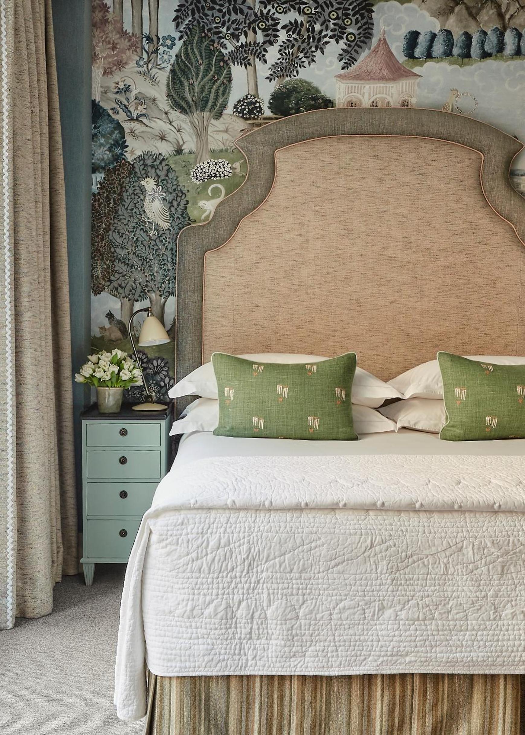 Hand-painted chinoiserie wallpaper creates an enchanting backdrop for natural linen headboards and sage green accent pillows in this thoughtfully curated guest room.